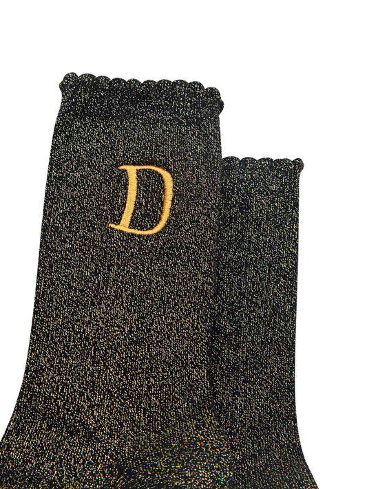 close up of the gold embroidered capital letter d on the ankle of the socks