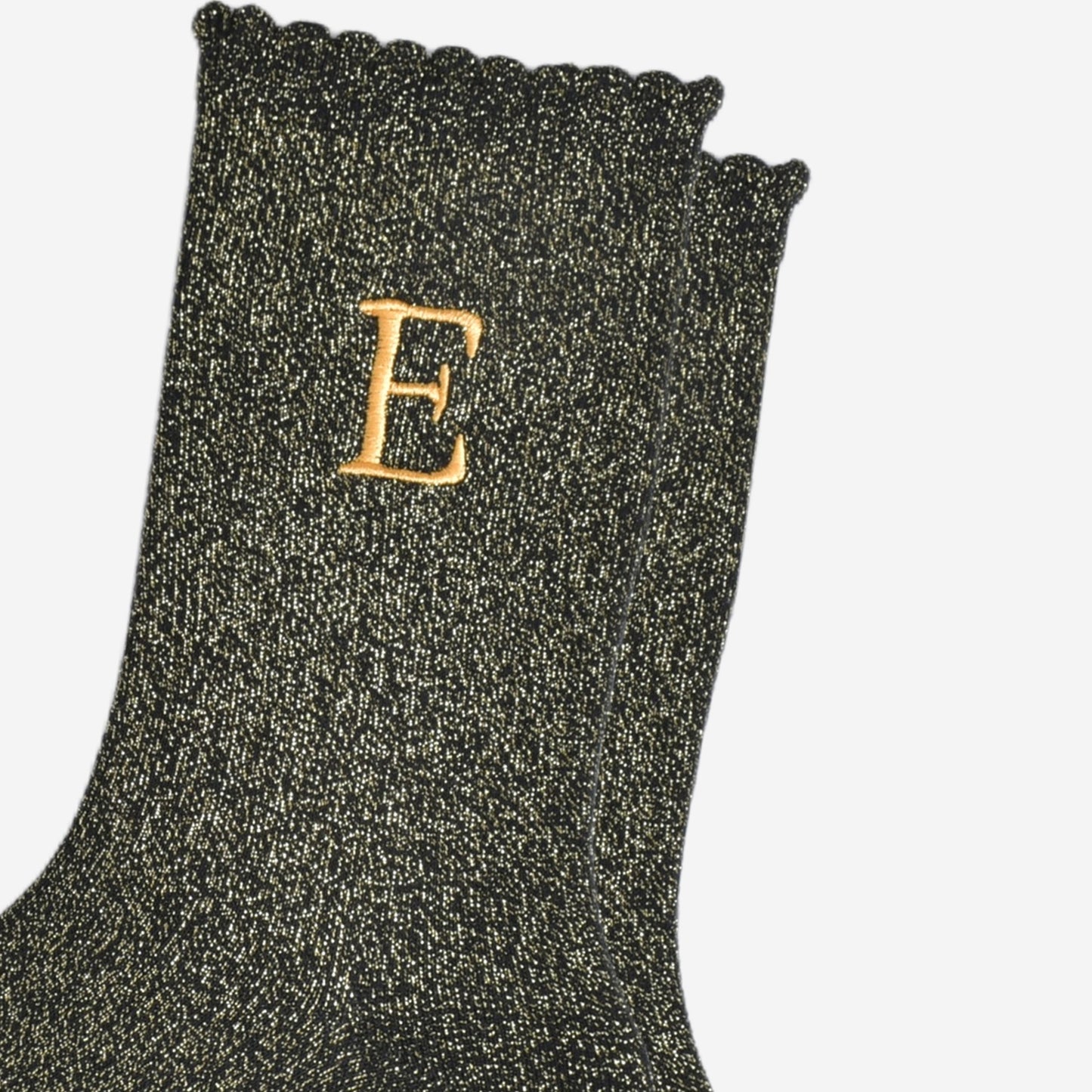 close up of the gold embroidered capital letter e on the ankle of the socks
