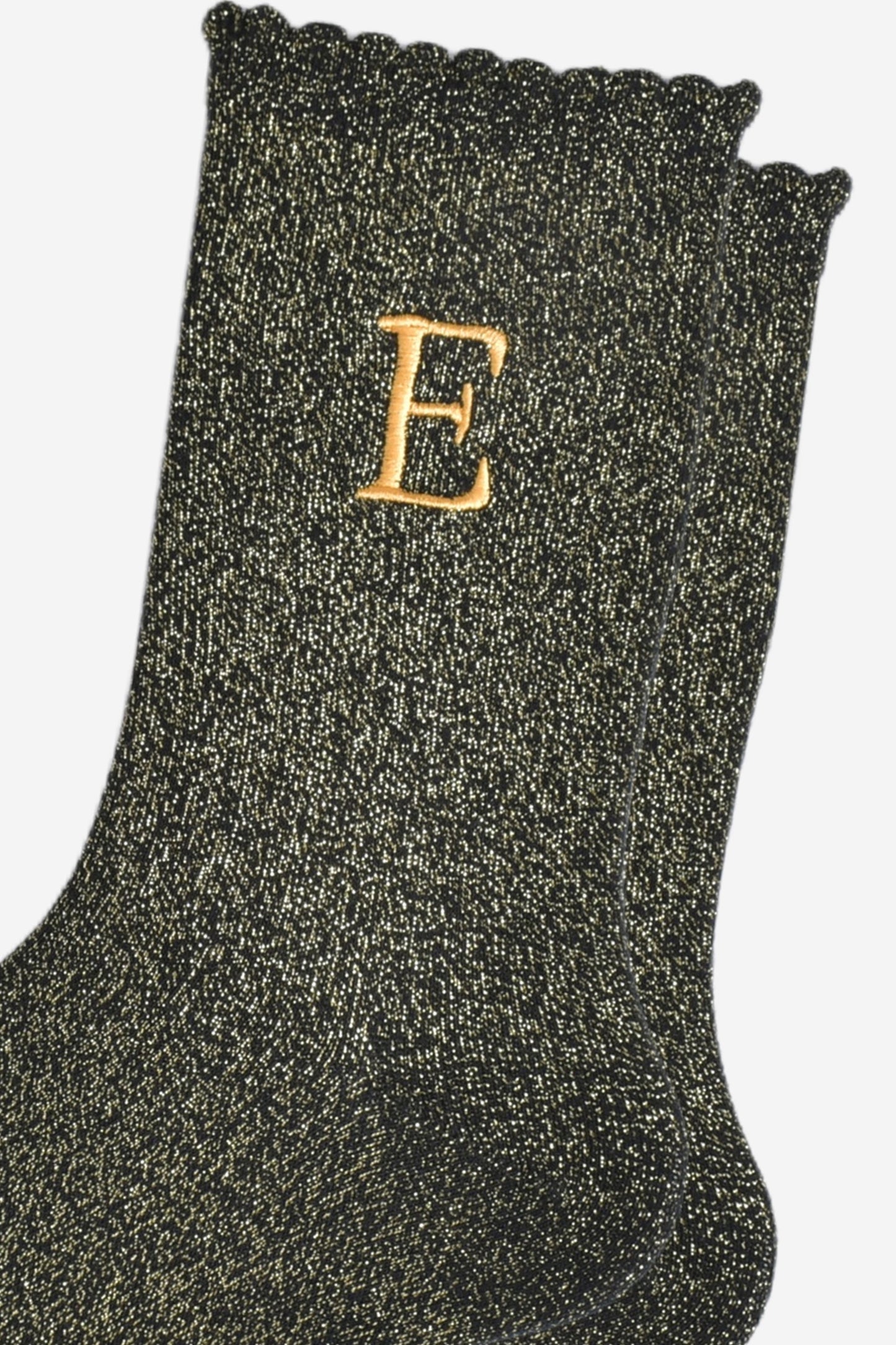 close up of the gold embroidered capital letter e on the ankle of the socks