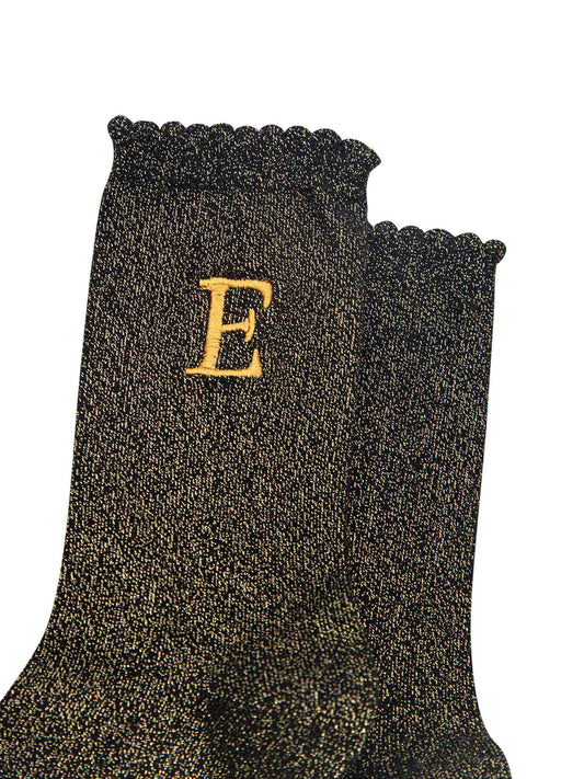 close up of the gold embroidered capital letter e on the ankle of the socks