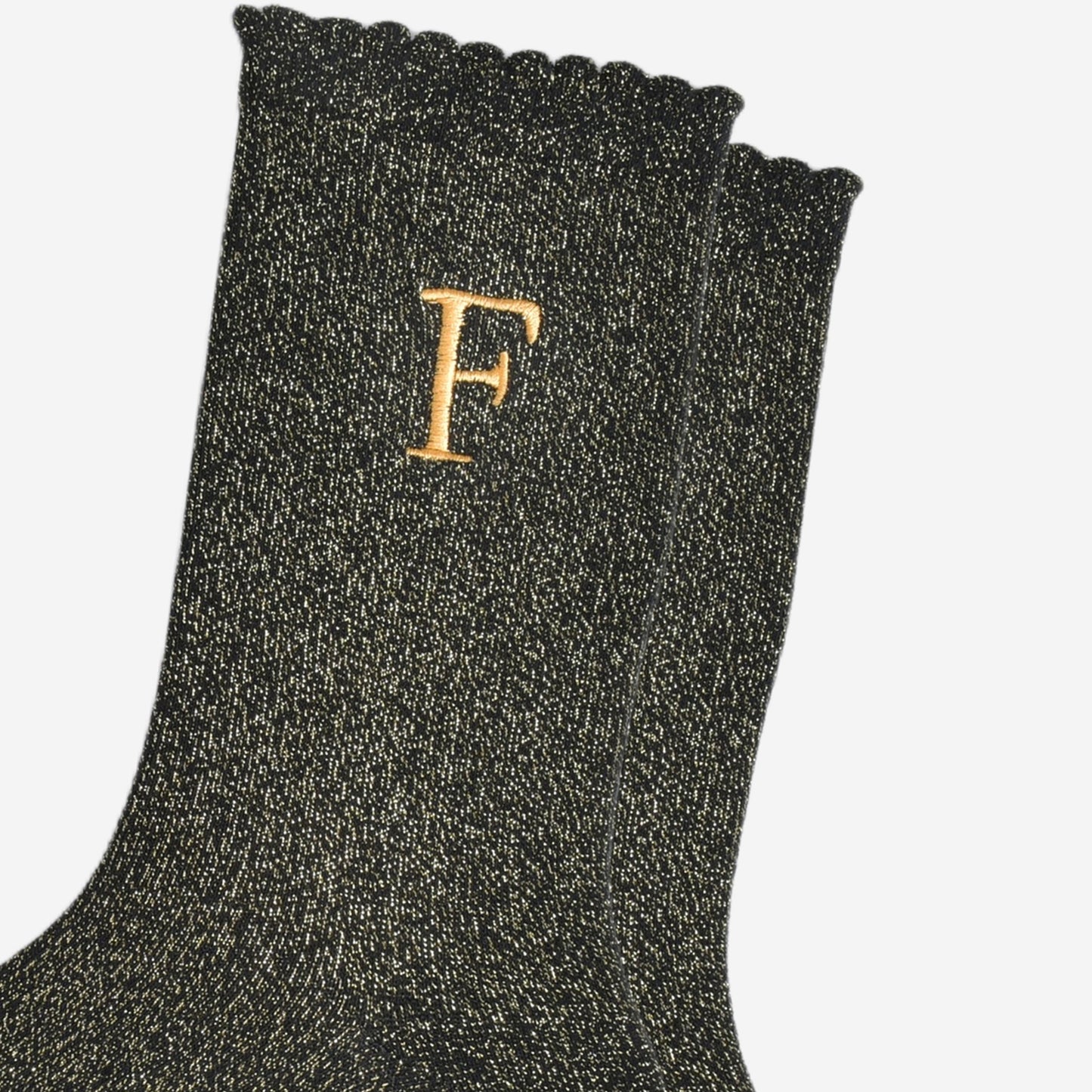 close up of the gold embroidered capital letter f on the ankle of the socks