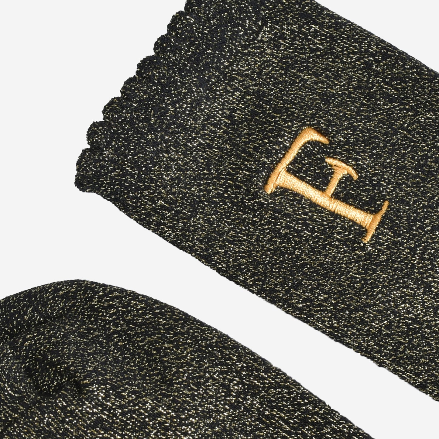 close up of the scalloped cuff on the socks, the toe is the same black and gold as the rest of the socks