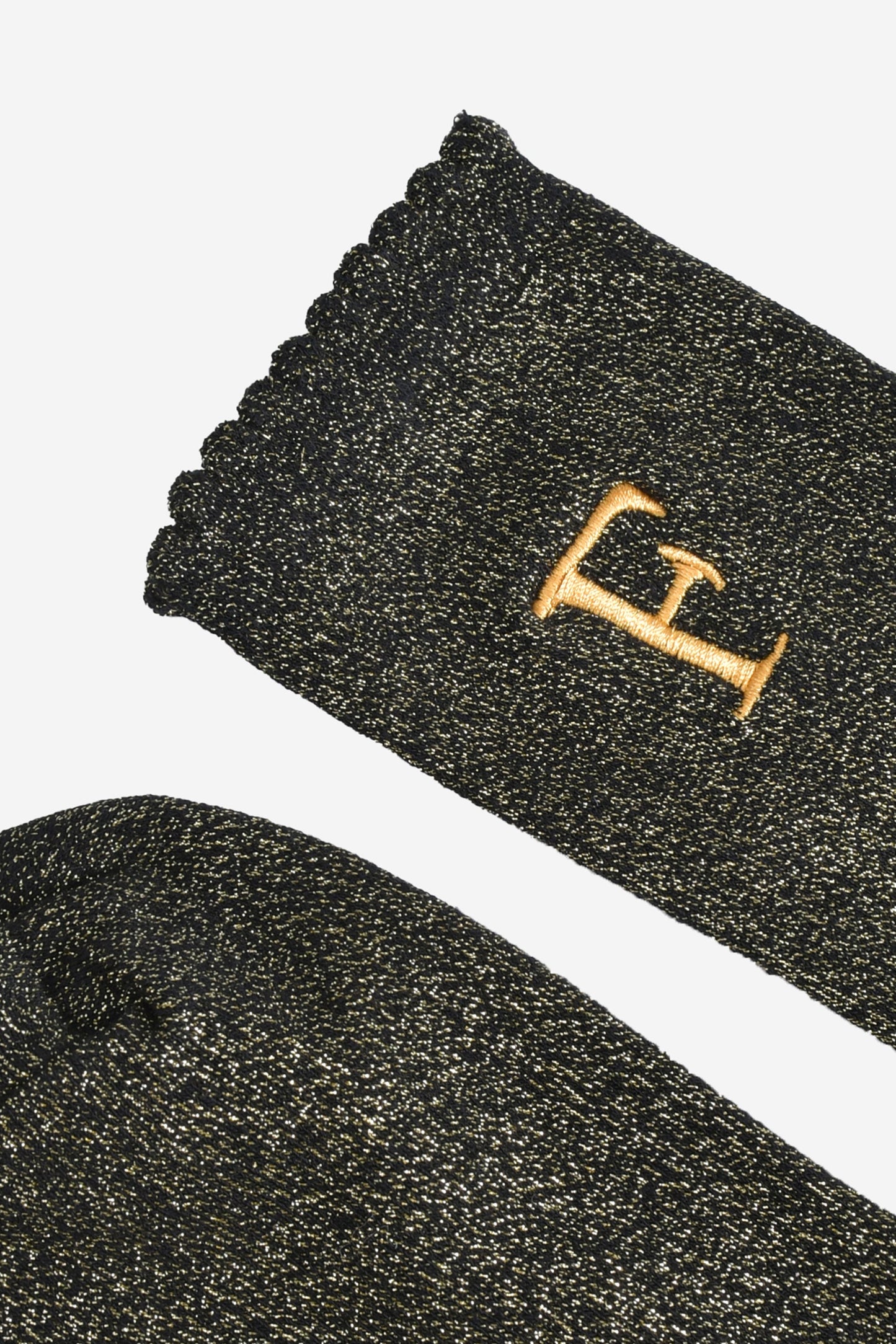close up of the scalloped cuff on the socks, the toe is the same black and gold as the rest of the socks