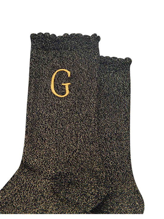 close up of the gold embroidered capital letter g on the ankle of the socks