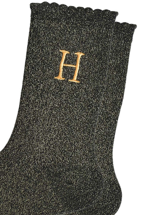close up of the gold embroidered capital letter h on the ankle of the socks