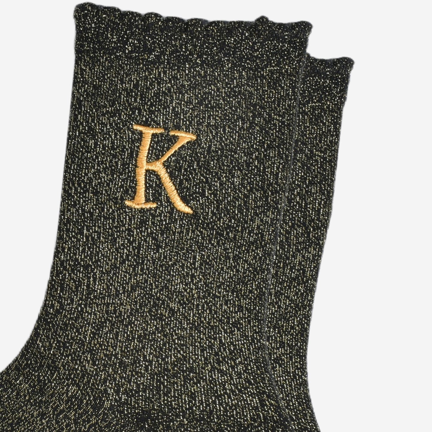 close up of the gold embroidered capital letter k on the ankle of the socks