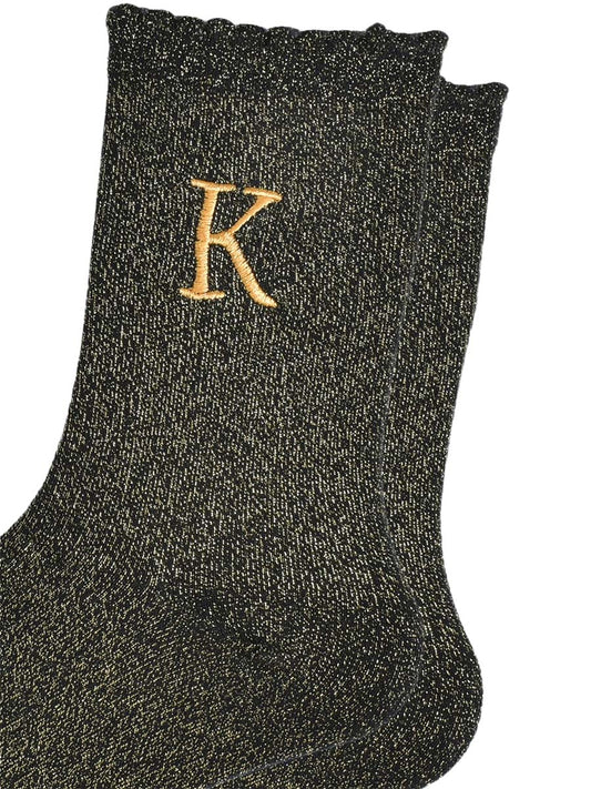 close up of the gold embroidered capital letter k on the ankle of the socks