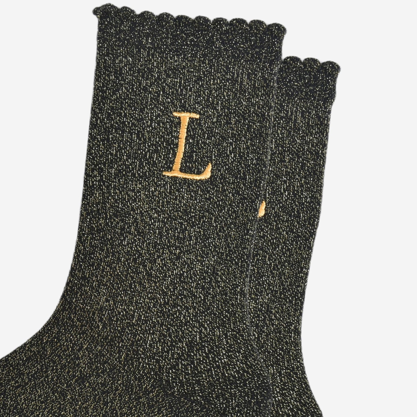 close up of the gold embroidered capital letter l on the ankle of the socks