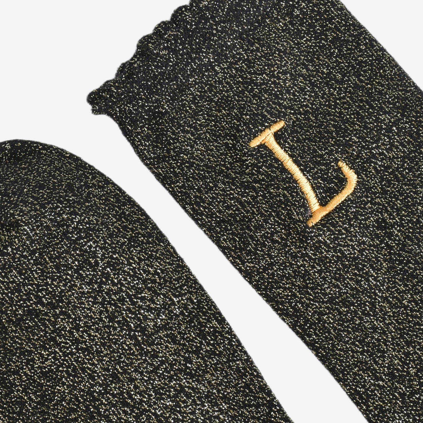 close up of the scalloped cuff on the socks, the toe is the same black and gold as the rest of the socks