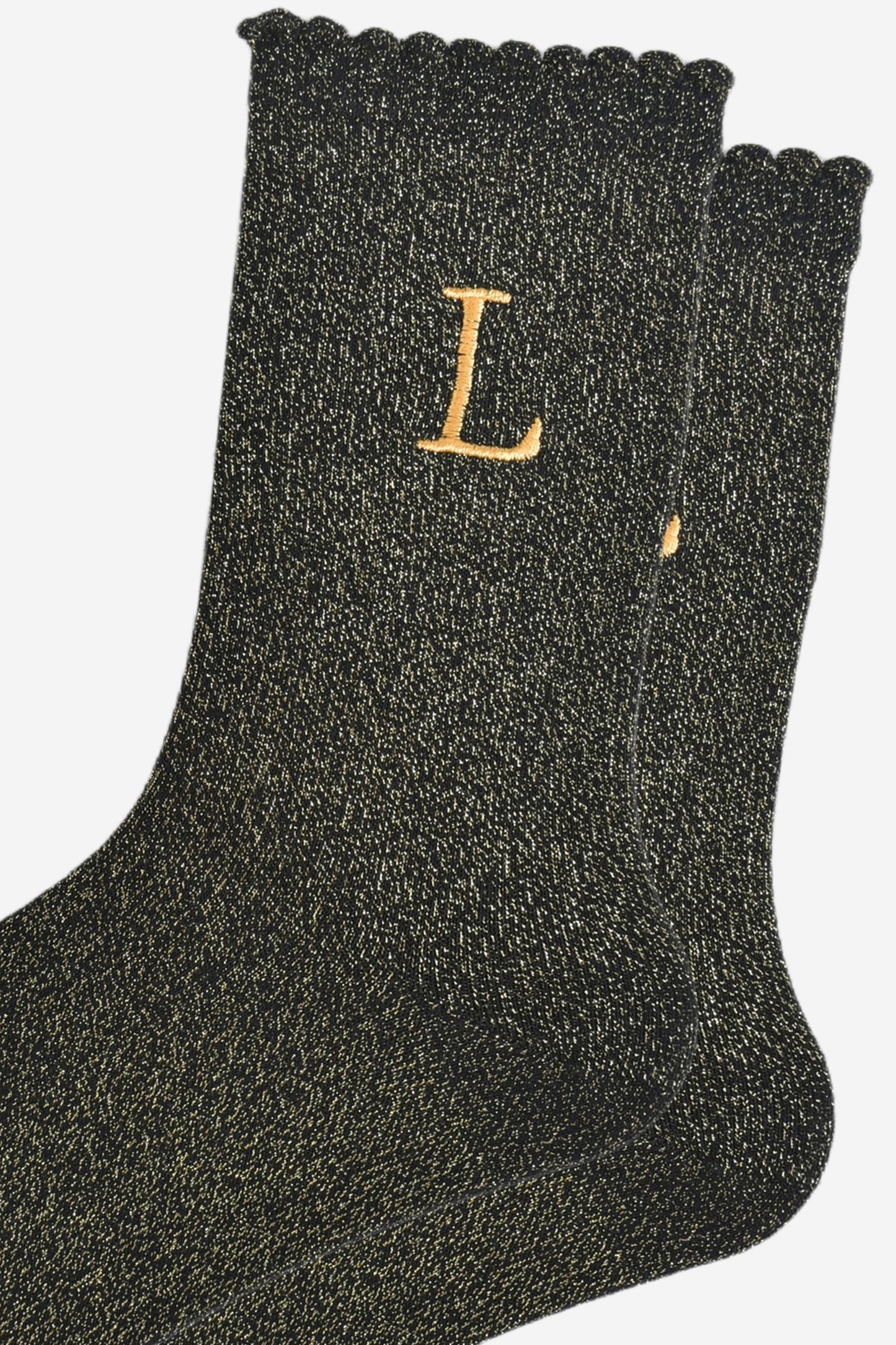 close up of the gold embroidered capital letter l on the ankle of the socks
