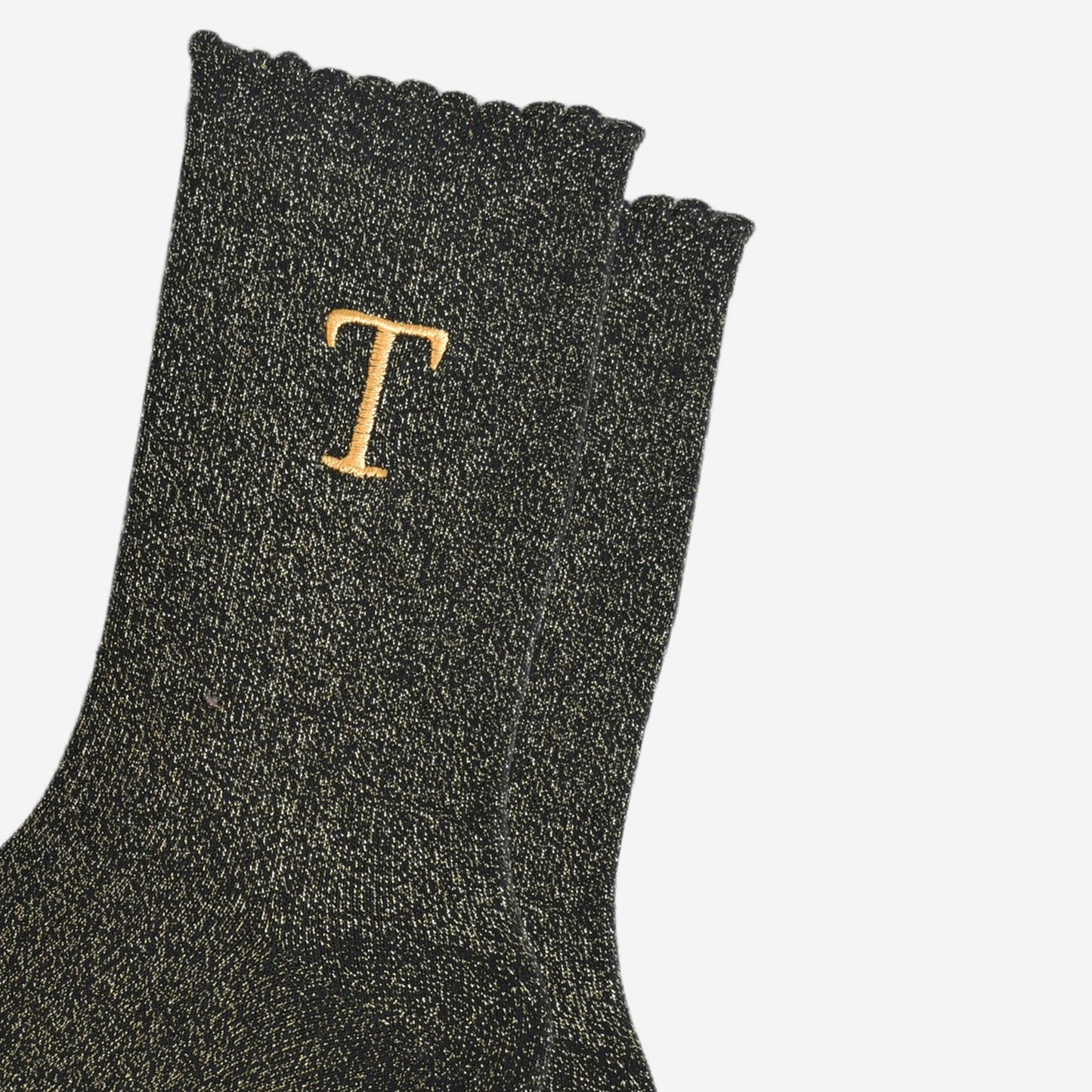 close up of the gold embroidered capital letter t on the ankle of the socks