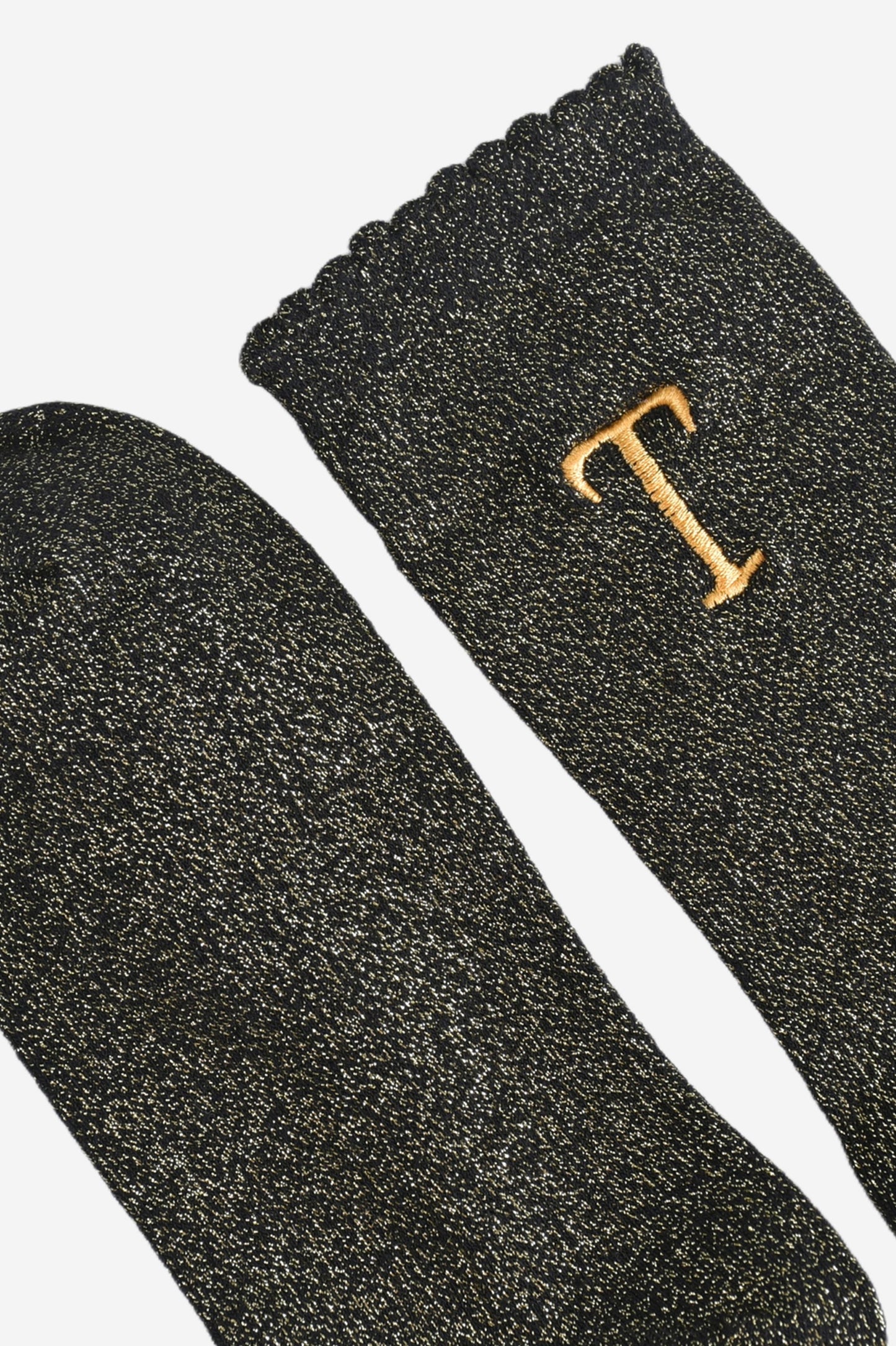 close up of the scalloped cuff on the socks, the toe is the same black and gold as the rest of the socks