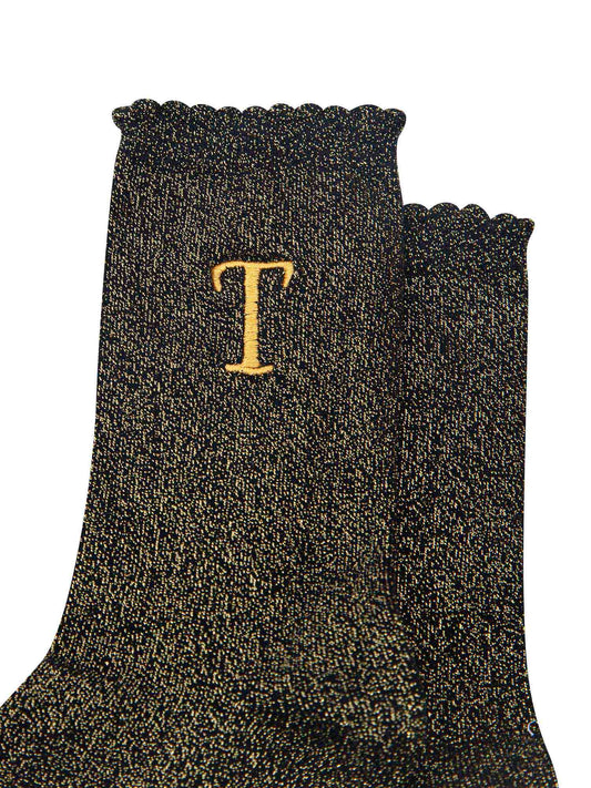 close up of the gold embroidered capital letter t on the ankle of the socks