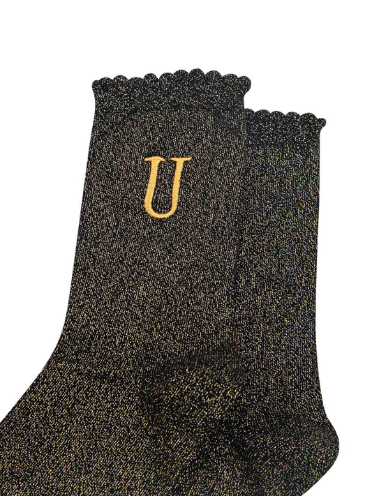 close up of the gold embroidered capital letter u on the ankle of the socks