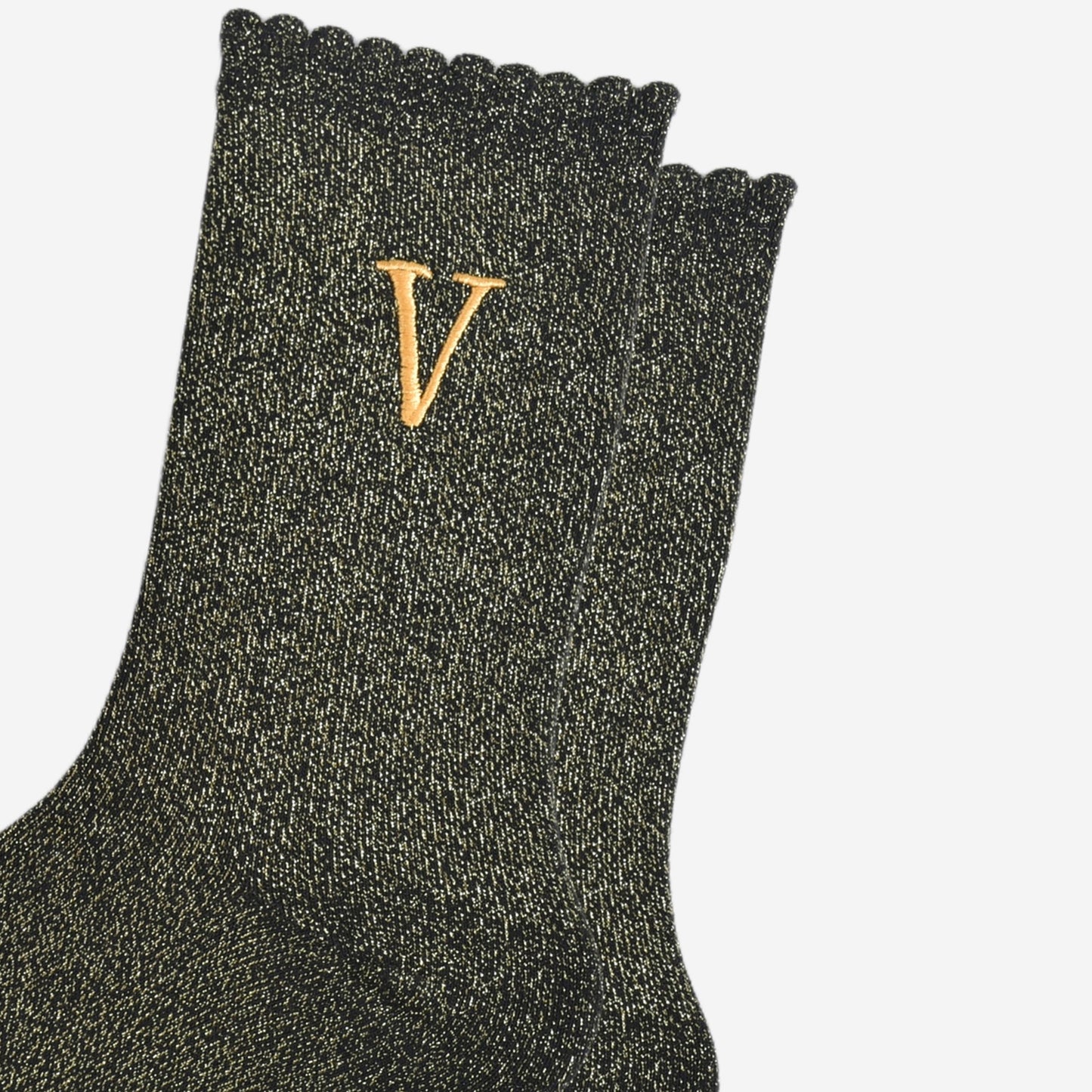 close up of the gold embroidered capital letter v on the ankle of the socks