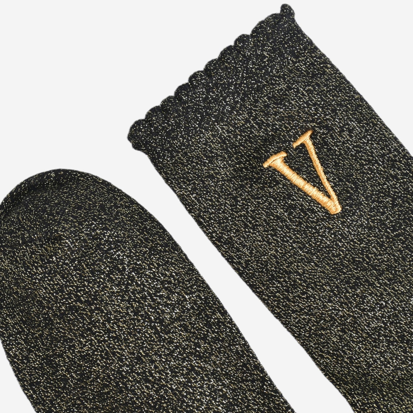 close up of the scalloped cuff on the socks, the toe is the same black and gold as the rest of the socks
