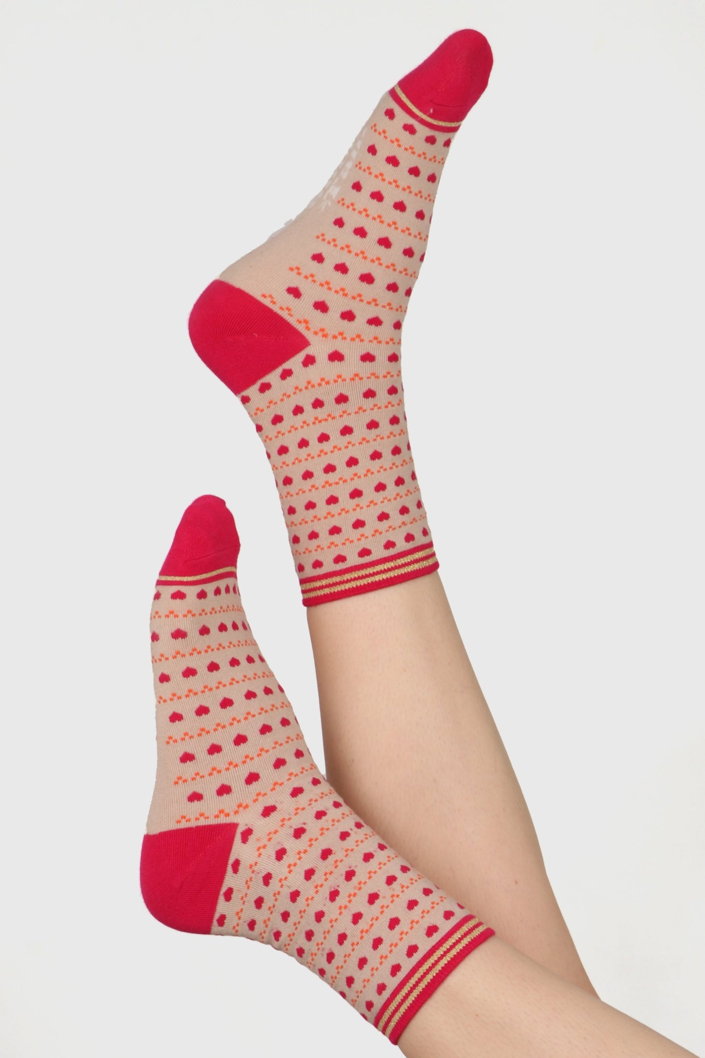 Ladies feet in the air wearing bamboo socks. Socka have all over heart and dot print on a cream base with contrasting toe and heel detail in pink