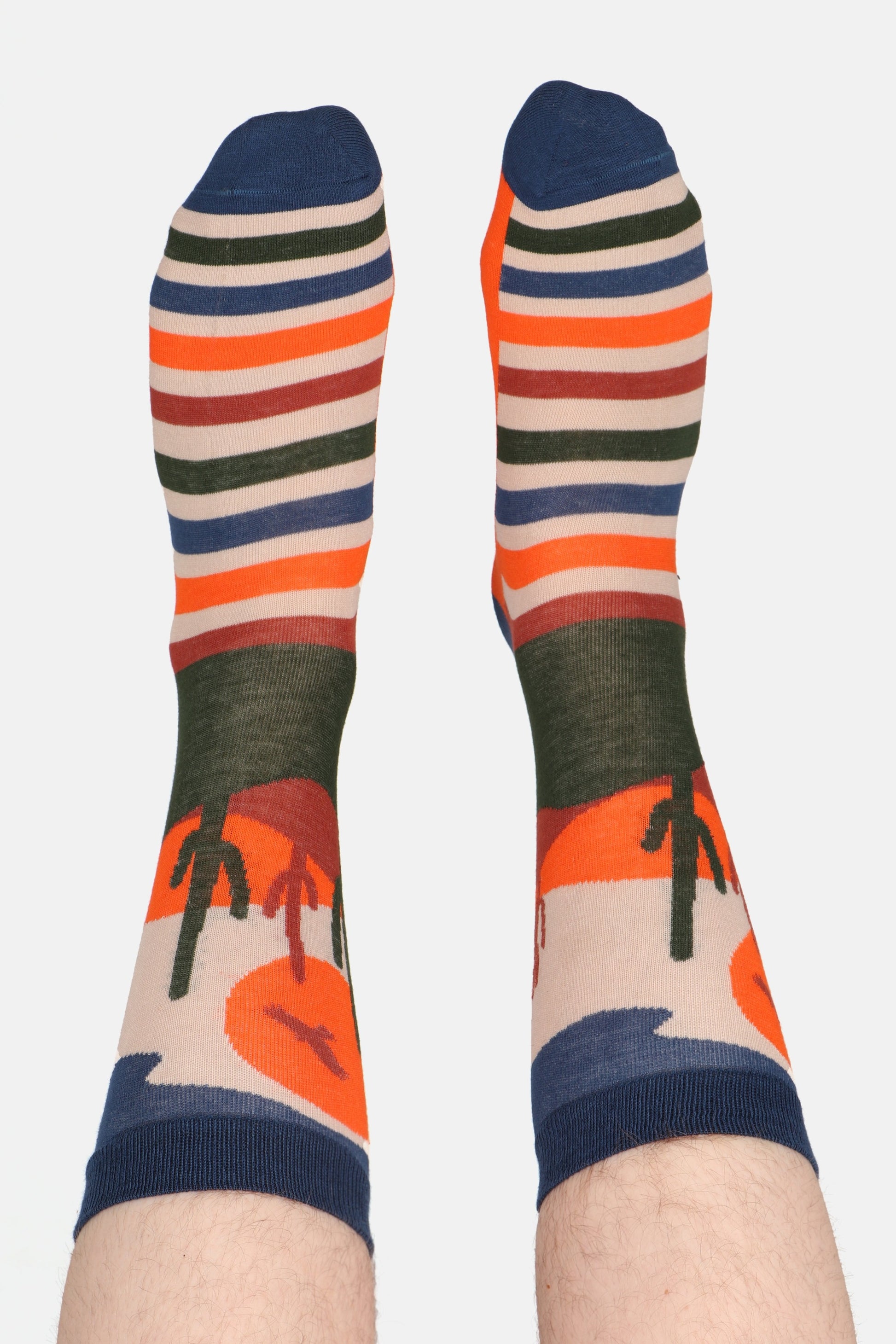 Male feet in the air wearing sock talk bamboo socks. Socks are printed with cactus and are wild west themed