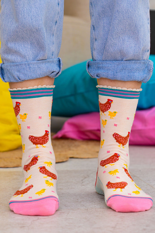 Person wearing colorful socks with chicken patterns on a light background