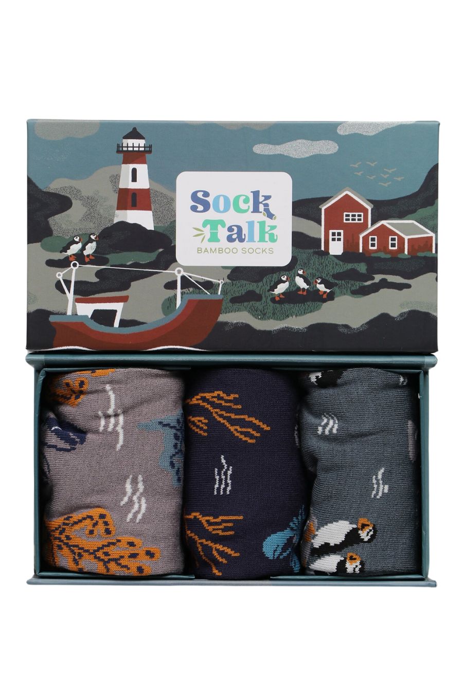 a gift box designed to look like a fishing village with a lighthouse, fishing boat and puffins with three pairs of mens bamboo socks