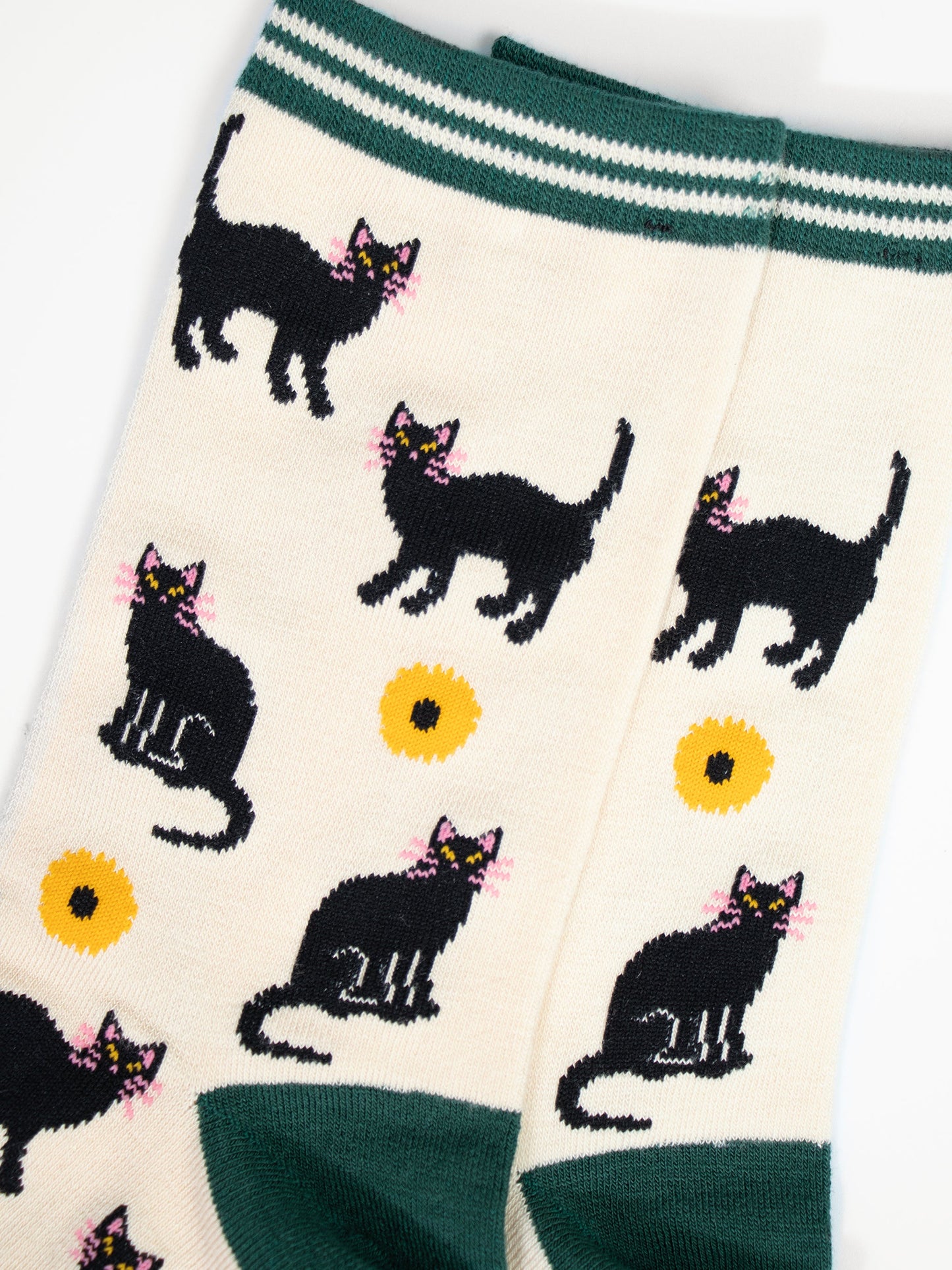 close up of the black cat and yellow sunflower design. the cats are standing and sitting and have pink whiskers, the sunflowers are yellow with a black centre.