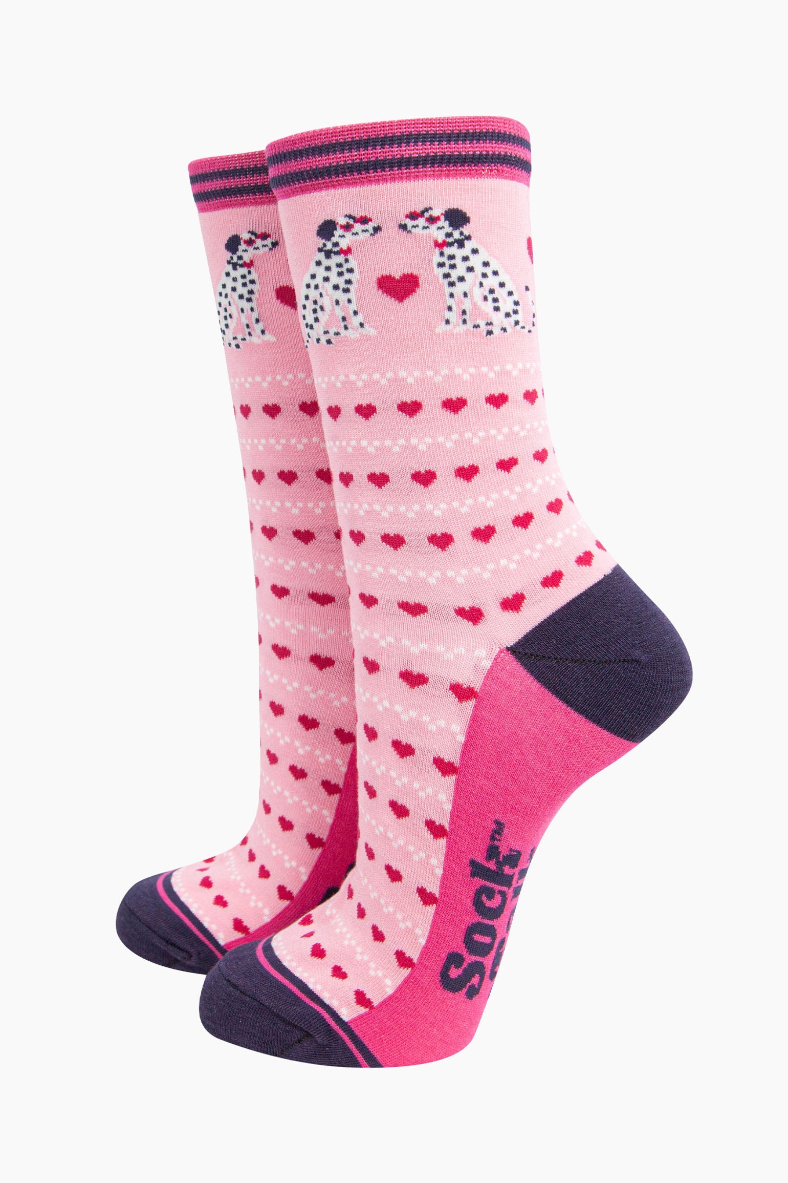 light pink bamboo socks with a pattern of pink love hearts and two dalmatians. the sole is fuchsia pink, the heel and toe are navy blue. the cuff of the socks is straight cut and has a navy blue and fuchsia pink stripe.