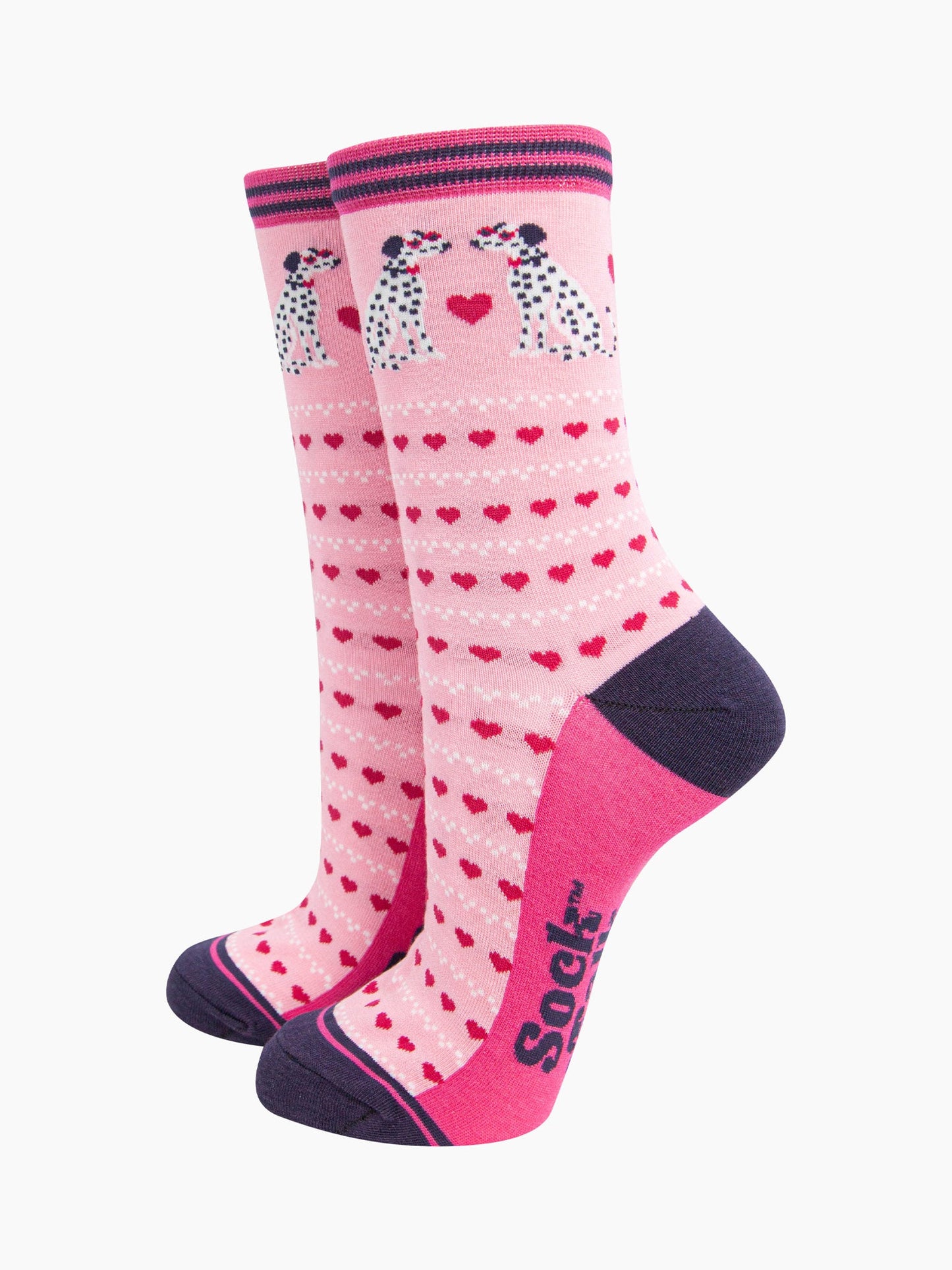 light pink bamboo socks with a pattern of pink love hearts and two dalmatians. the sole is fuchsia pink, the heel and toe are navy blue. the cuff of the socks is straight cut and has a navy blue and fuchsia pink stripe.