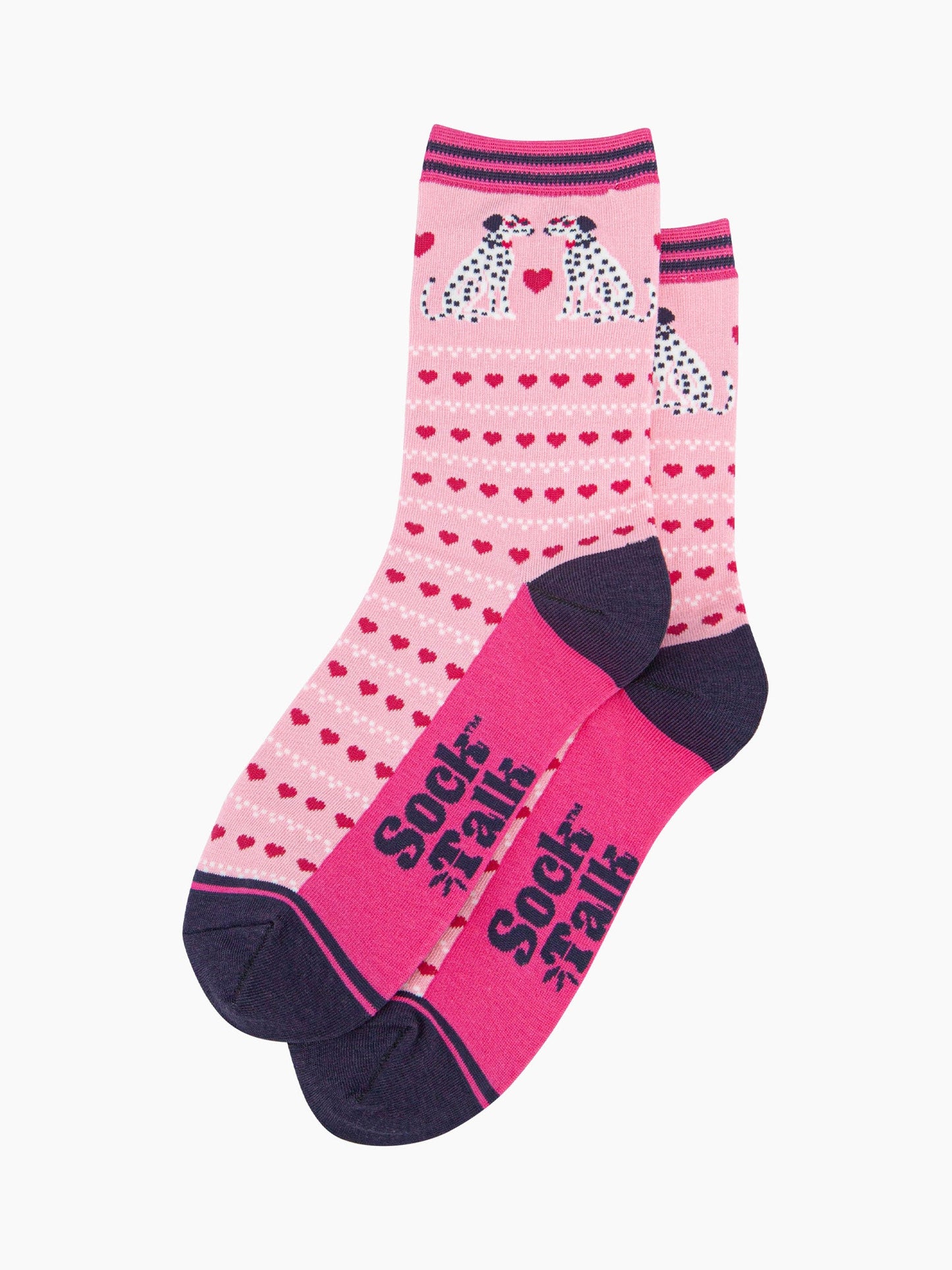 the pair of pink dalmatian dog socks laying flat, one overlapping the other. showing clearly the light pink background of the socks which is contrasted by the repeating rows of fuchsia pink love hearts. the dalmatians feature on the ankle of the socks. the sock talk logo is visible on the base of the sole. 