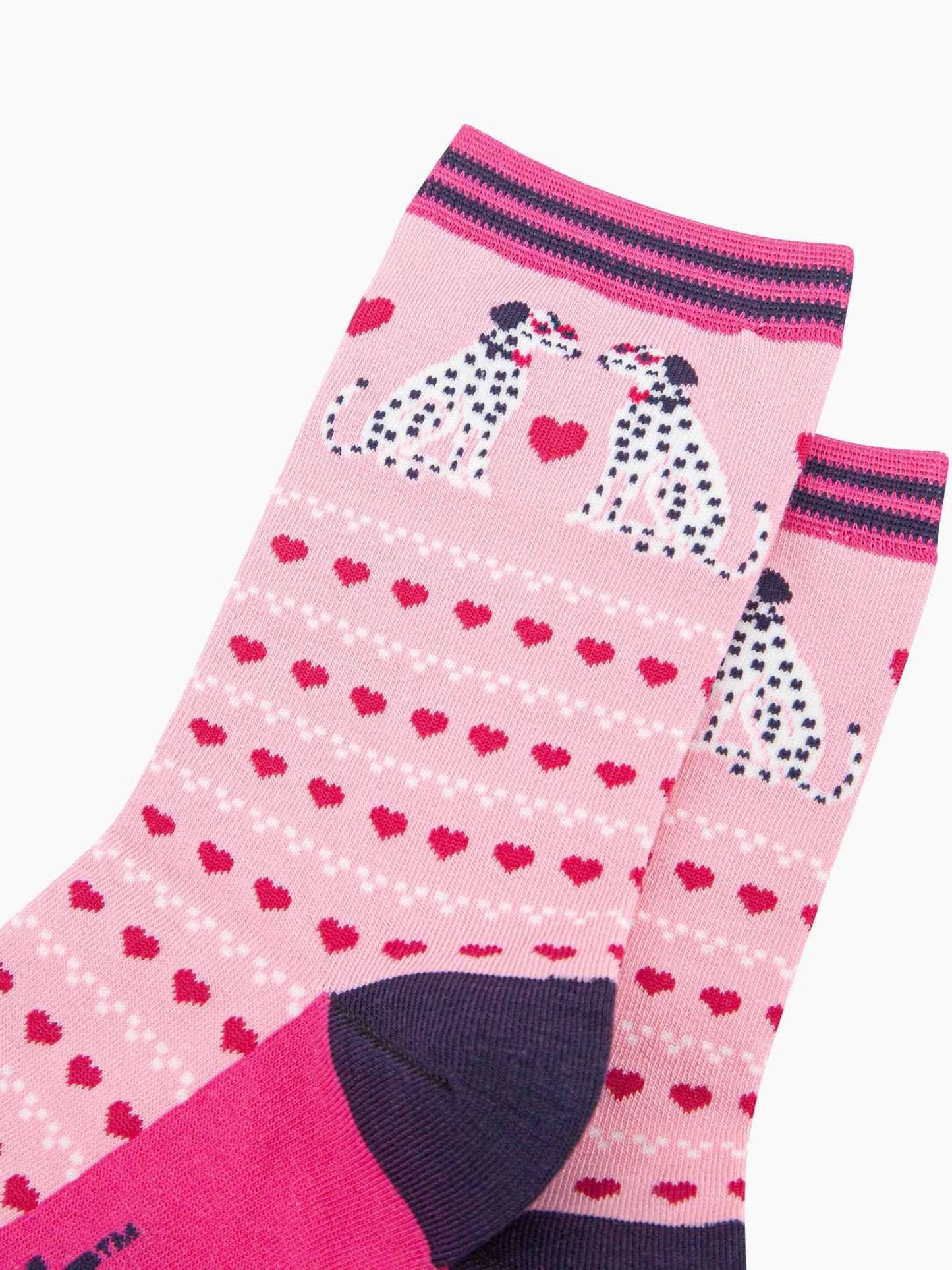 close up of the pattern. the pair of dalmatian dogs on the ankle are facing each other. Each dog is wearing a pair of pink sunglasses and a bowtie. between the sitting dalmatians is a large fuchsia pink love heart. the body of the sock is covered in rows of fuchsia pink love hearts and rows of  white dots.