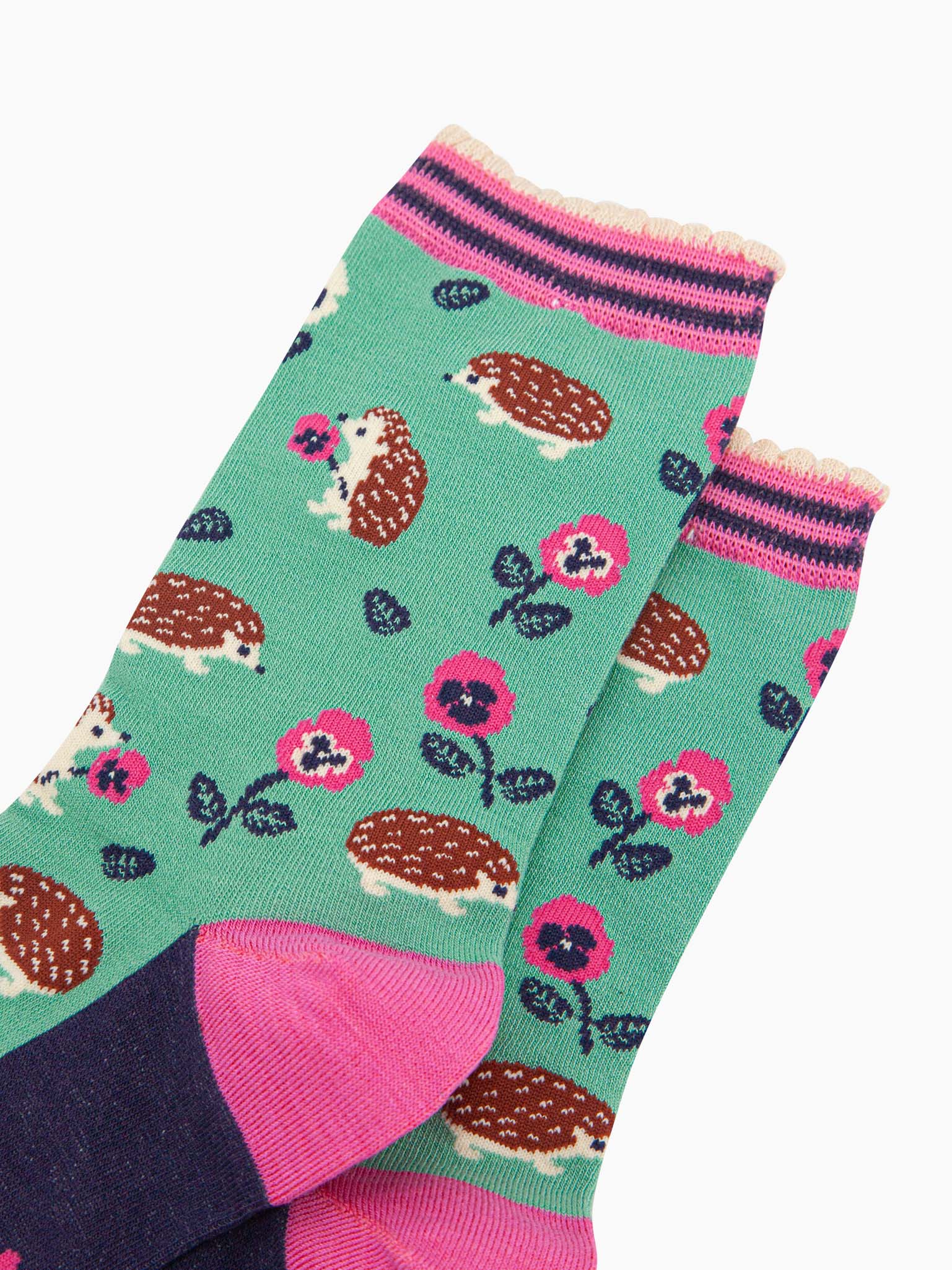 close up of the pattern. the hedgehogs are brown and beige, some are sitting holding pink pansy flowers, others are walking among the flowers. 