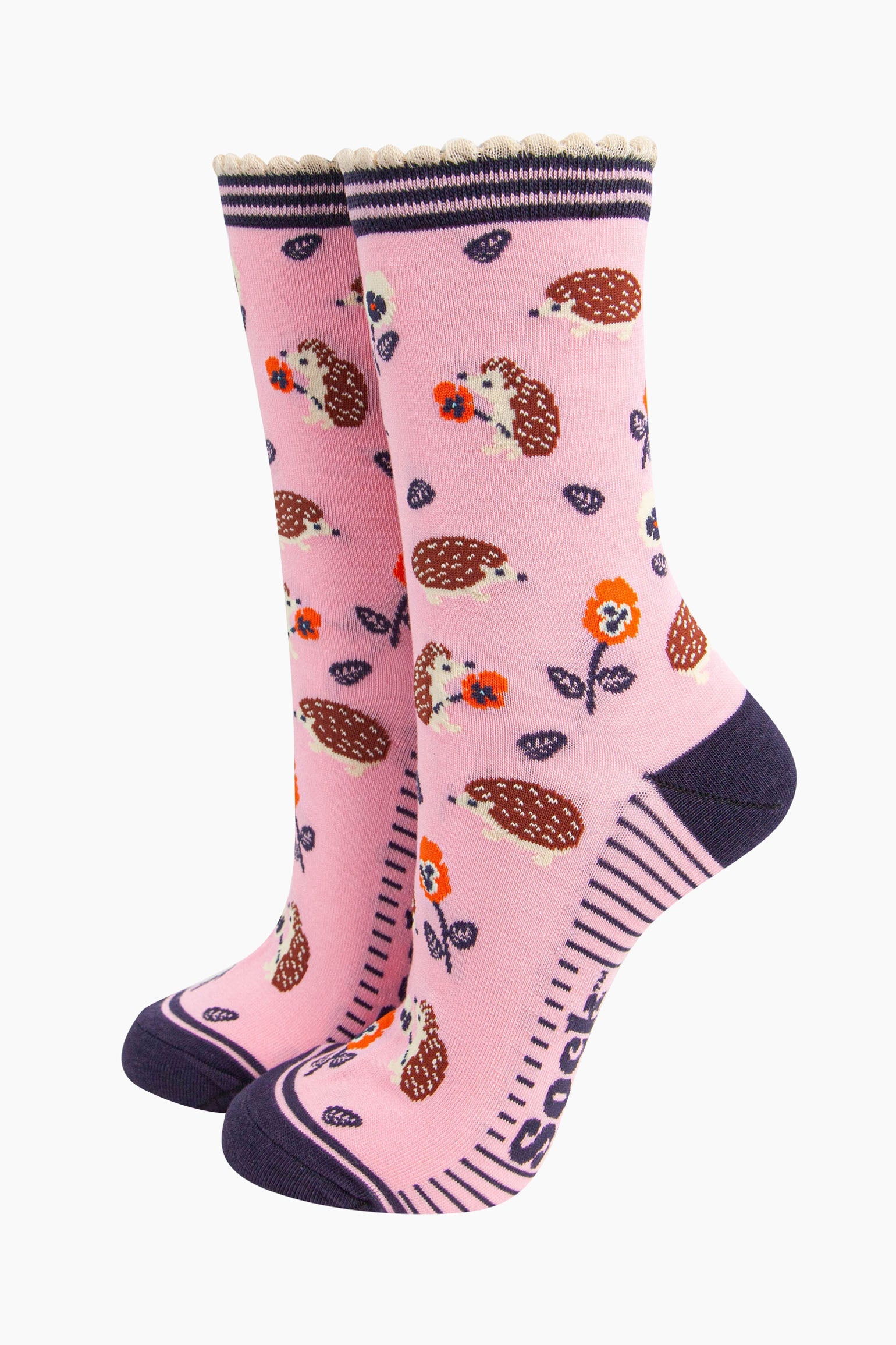  light pink bamboo socks with an all over pattern of woodland hedgehogs and orange pansy flowers. the socks have a contrasting navy blue heel and toe. the cuff is scalloped and is pink and navy striped.