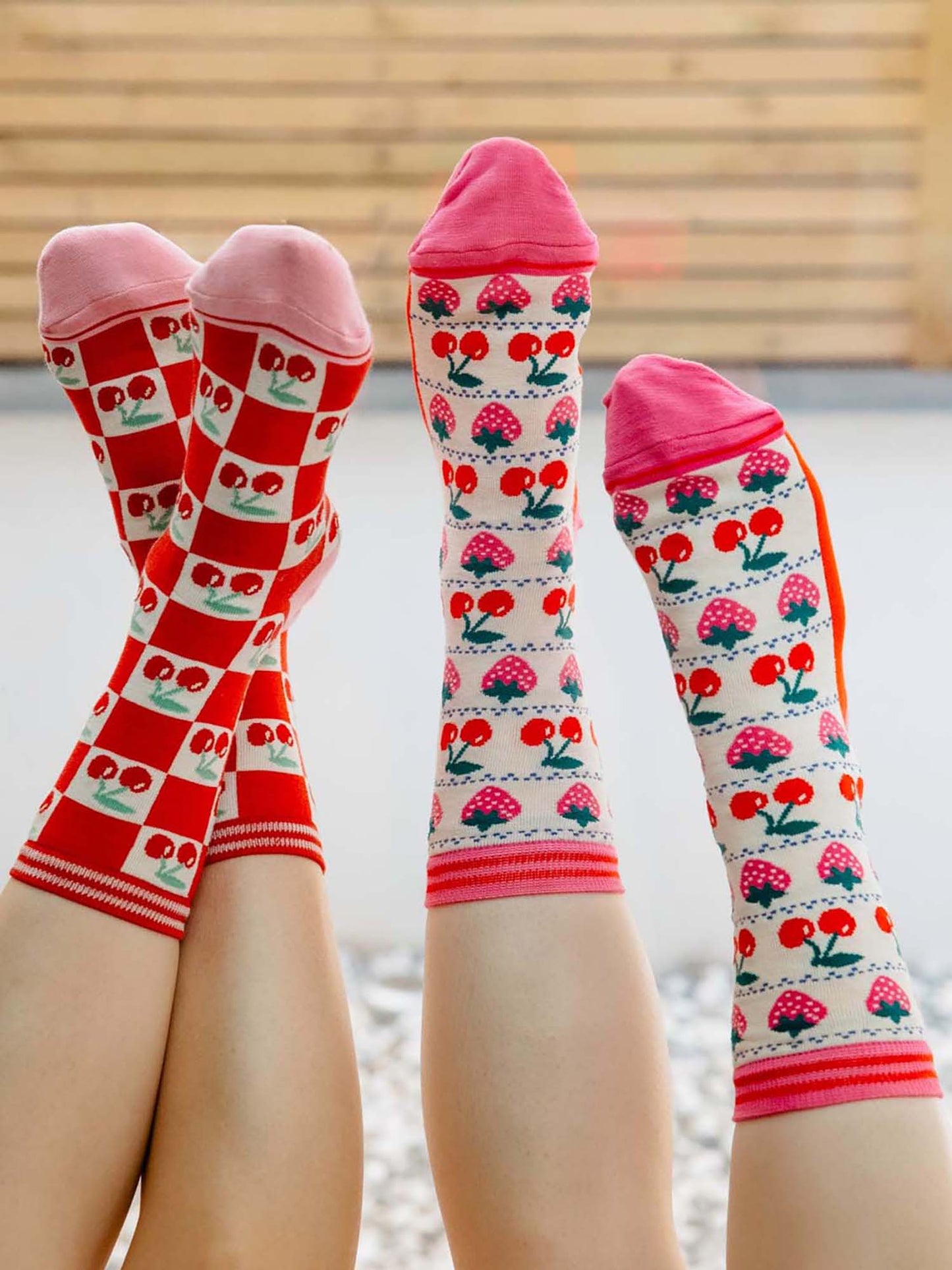 womens-bamboo-socks-cream-red-cherry-squares-and-womens-bamboo-socks-cream-strawberry-cherry-fair-isle-two-woemn-posed-feet-to-sky