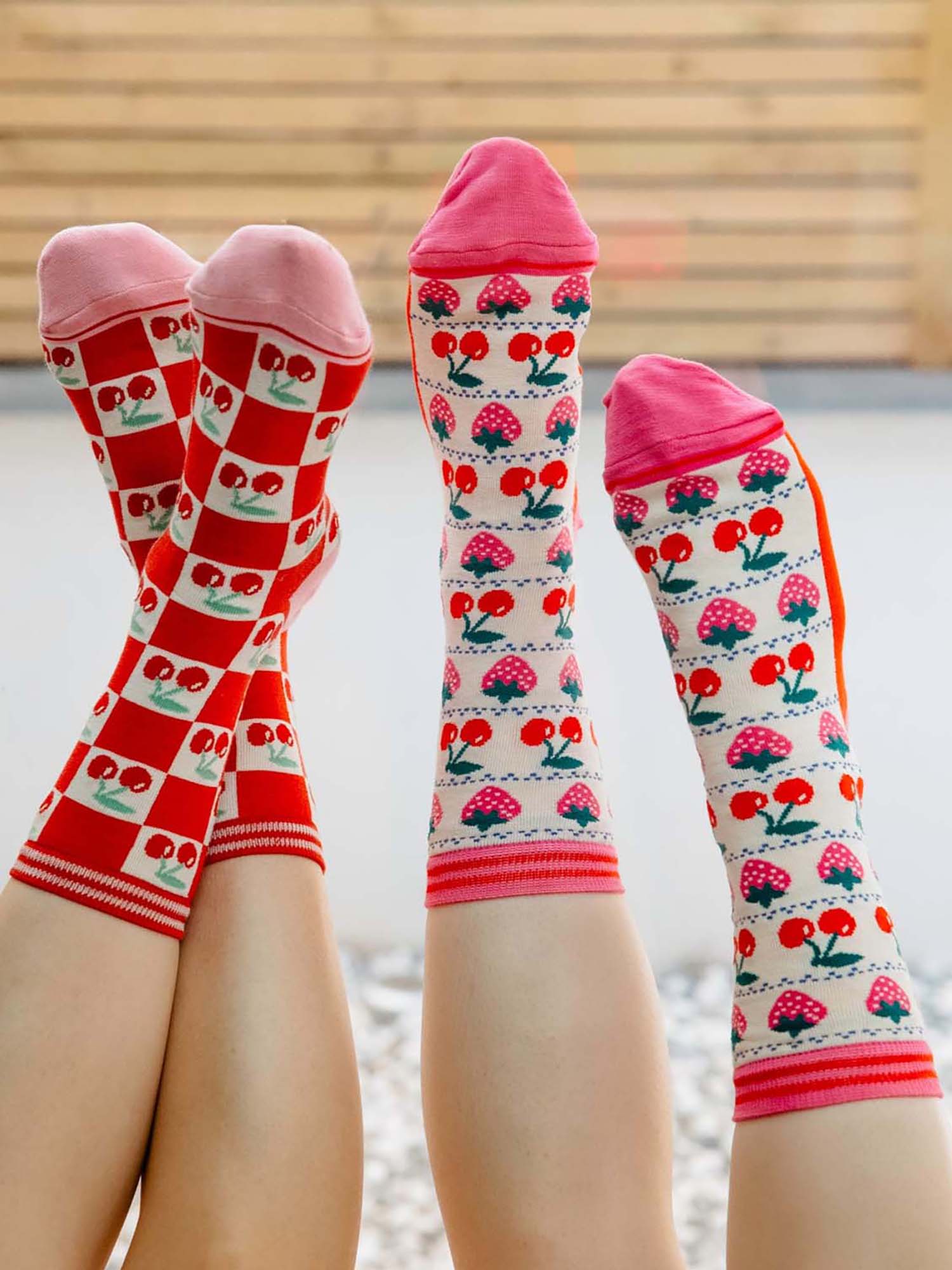 womens-bamboo-socks-cream-red-cherry-squares-and-womens-bamboo-socks-cream-strawberry-cherry-fair-isle-two-woemn-posed-feet-to-sky