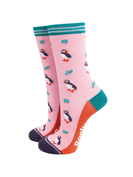 light pink bamboo socks with a pattern of black and white puffin birds and turquoise seashells. the socks have a turquoise and white striped cuff.