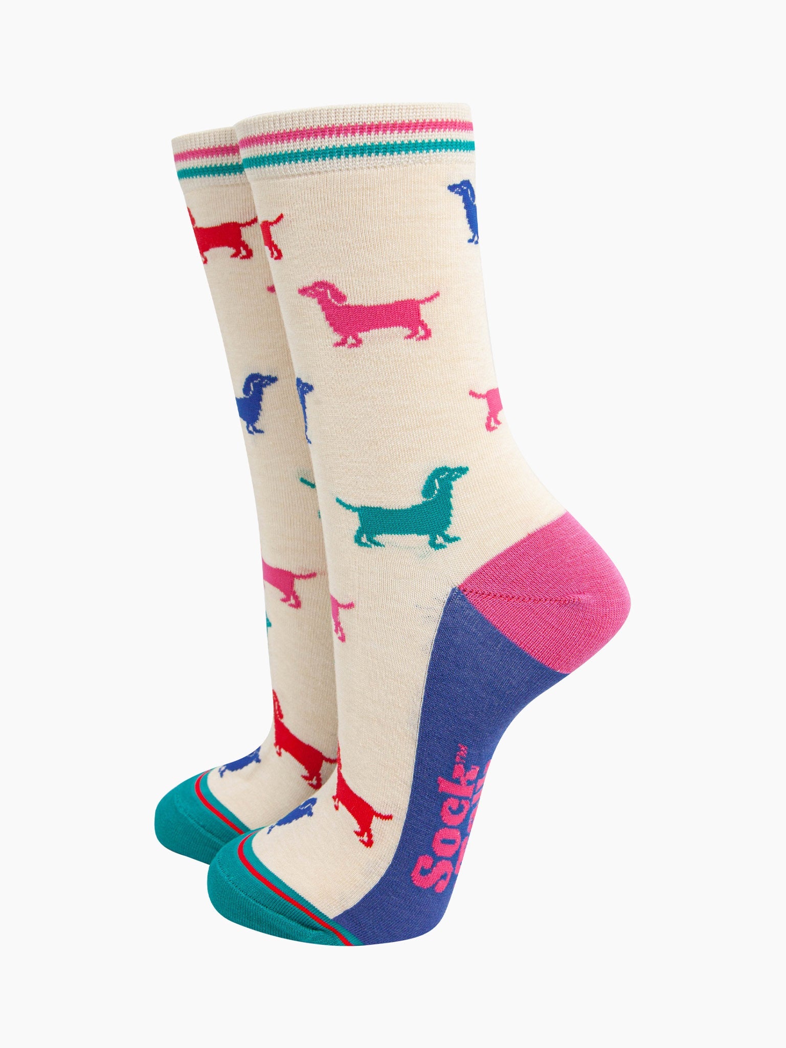 cream bamboo socks with a pattern of colourful sausage dogs. the sole is blue, heel is pink and the toe is turquoise. the cuff of the socks is straight cut and has a turquoise and pink stripe.