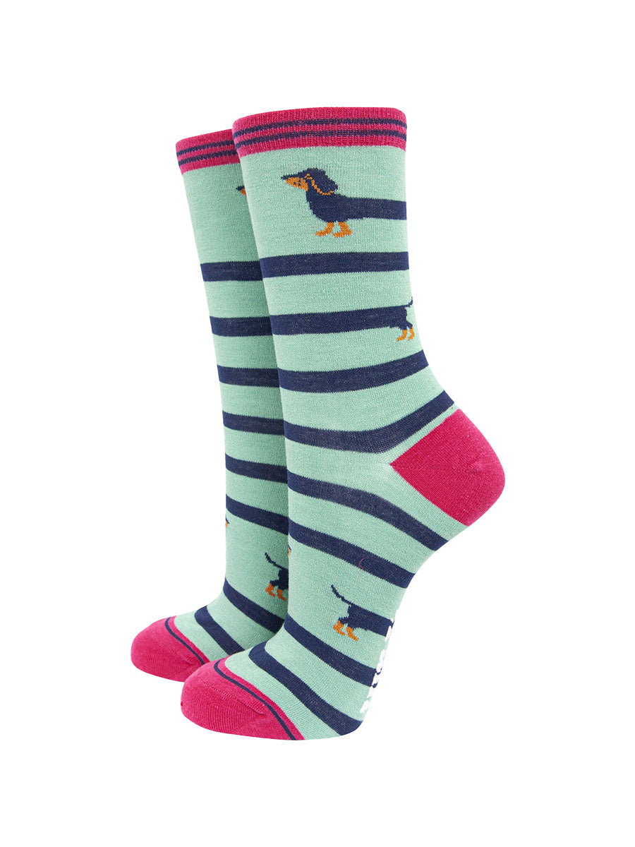 mint green ankle socks with pink heel, toe and cuff with a navy blue sausage dog winding itself around the sock giving the socks a striped appearance