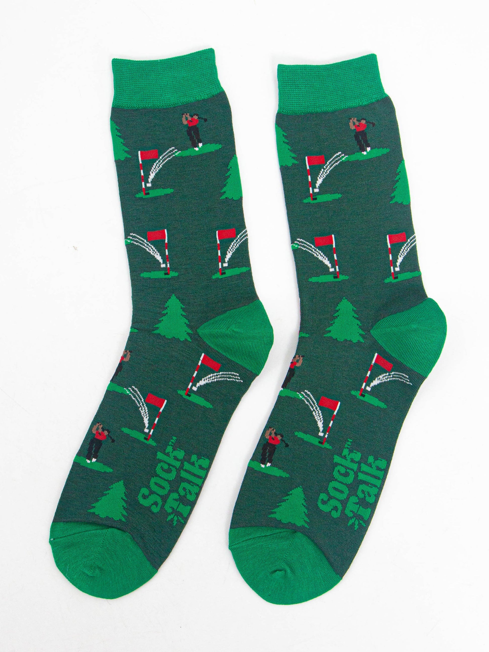 showing the socks laying flat, the golfer chipping the ball into the hole is visible all over the socks, there are also evergreen trees in the pattern