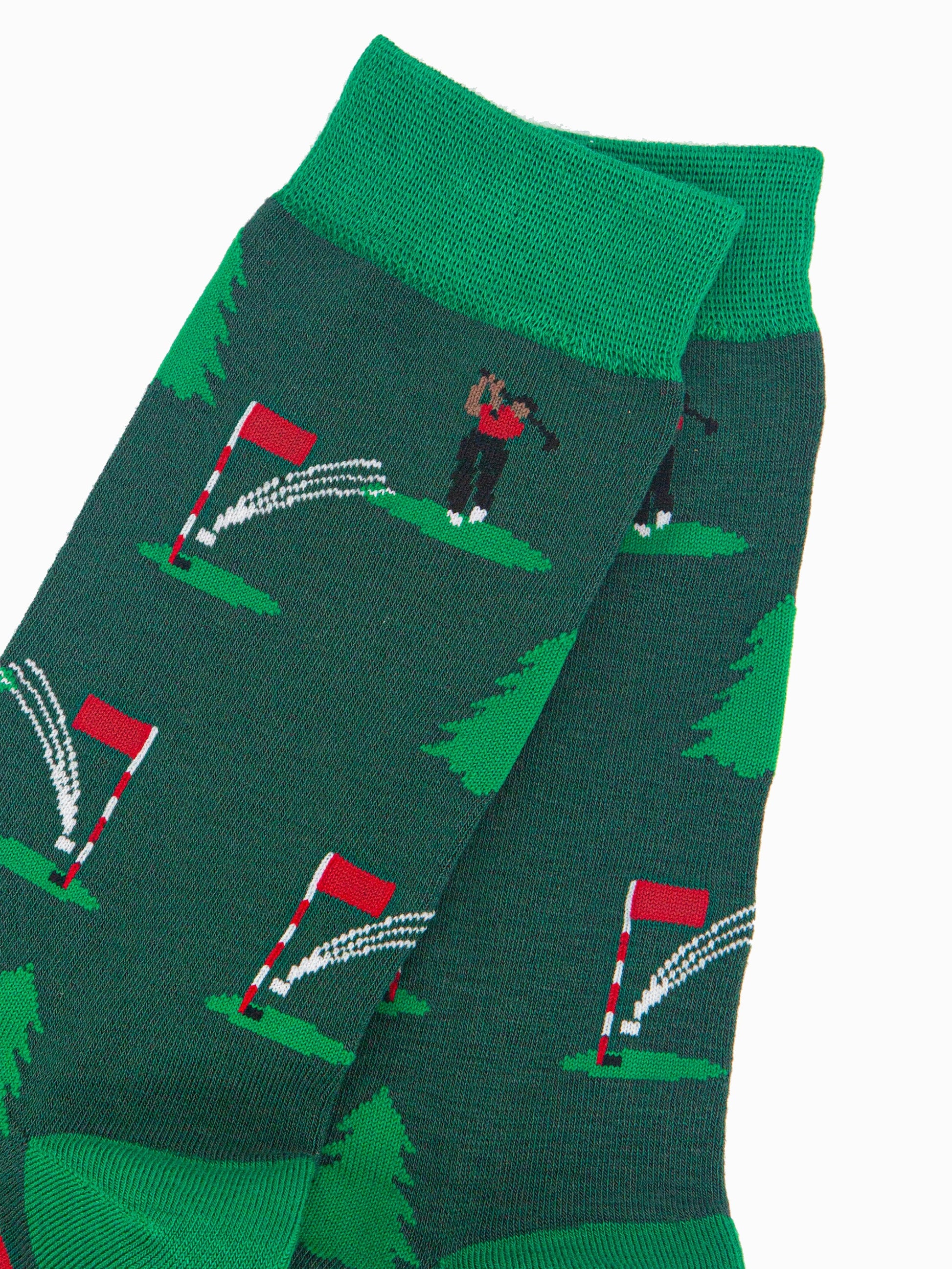 close up of the putting golfer pattern, the golfer is wearing a red shirt and is swinging the club behind his head, the ball is in the air and about to land in the hole on the green