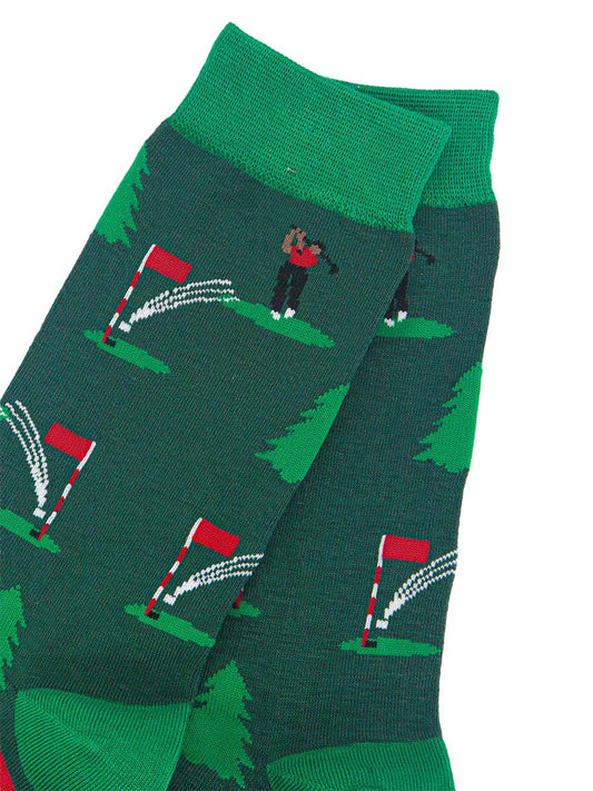 close up of the putting golfer pattern, the golfer is wearing a red shirt and is swinging the club behind his head, the ball is in the air and about to land in the hole on the green