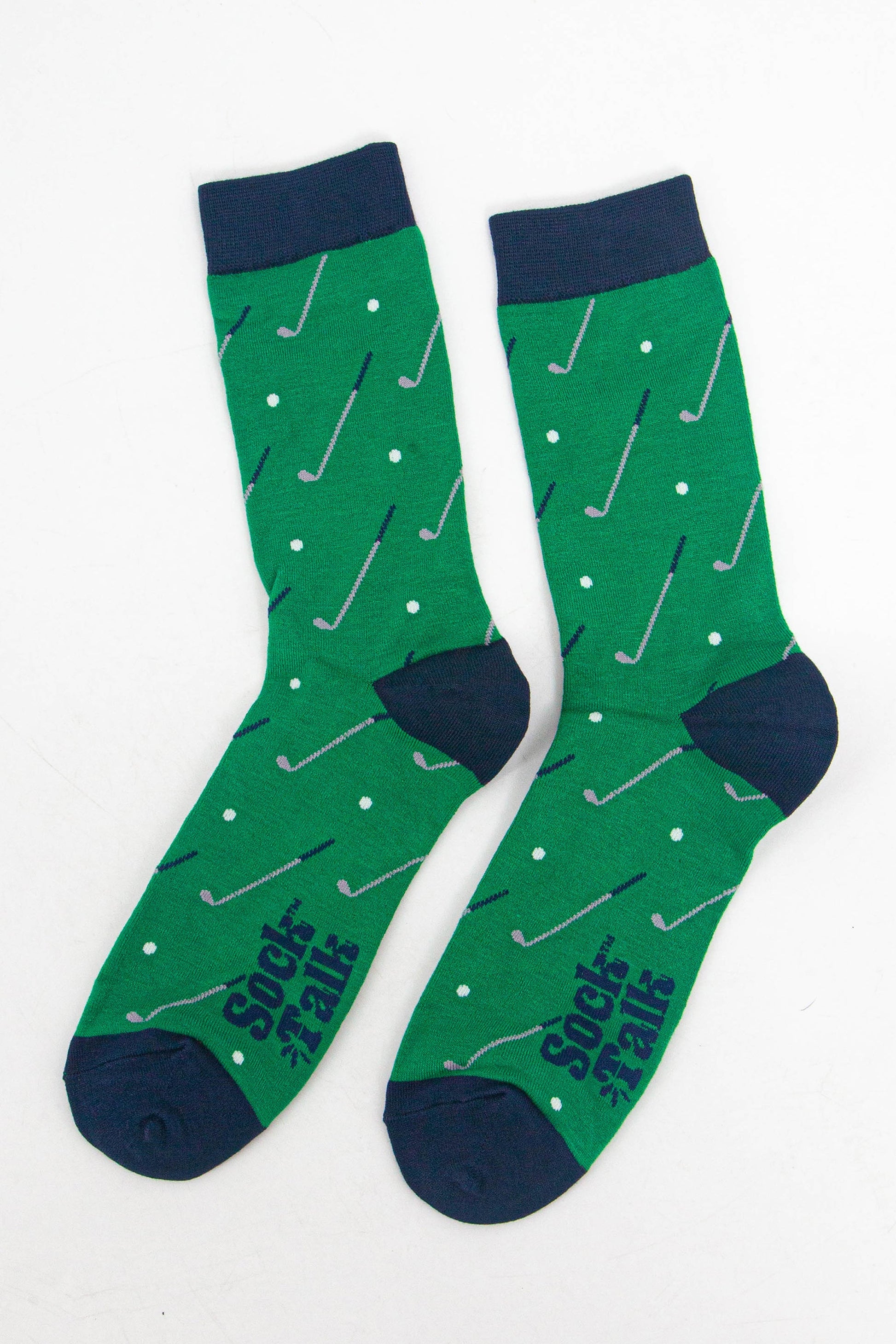 showing the socks laying flat, there is an all over pattern of golf clubs and golf balls on a green background