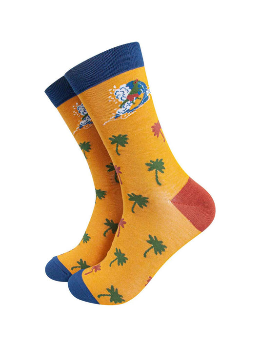 mens yellow bamboo socks featuring a surfing t-rex and an all over palm tree pattern