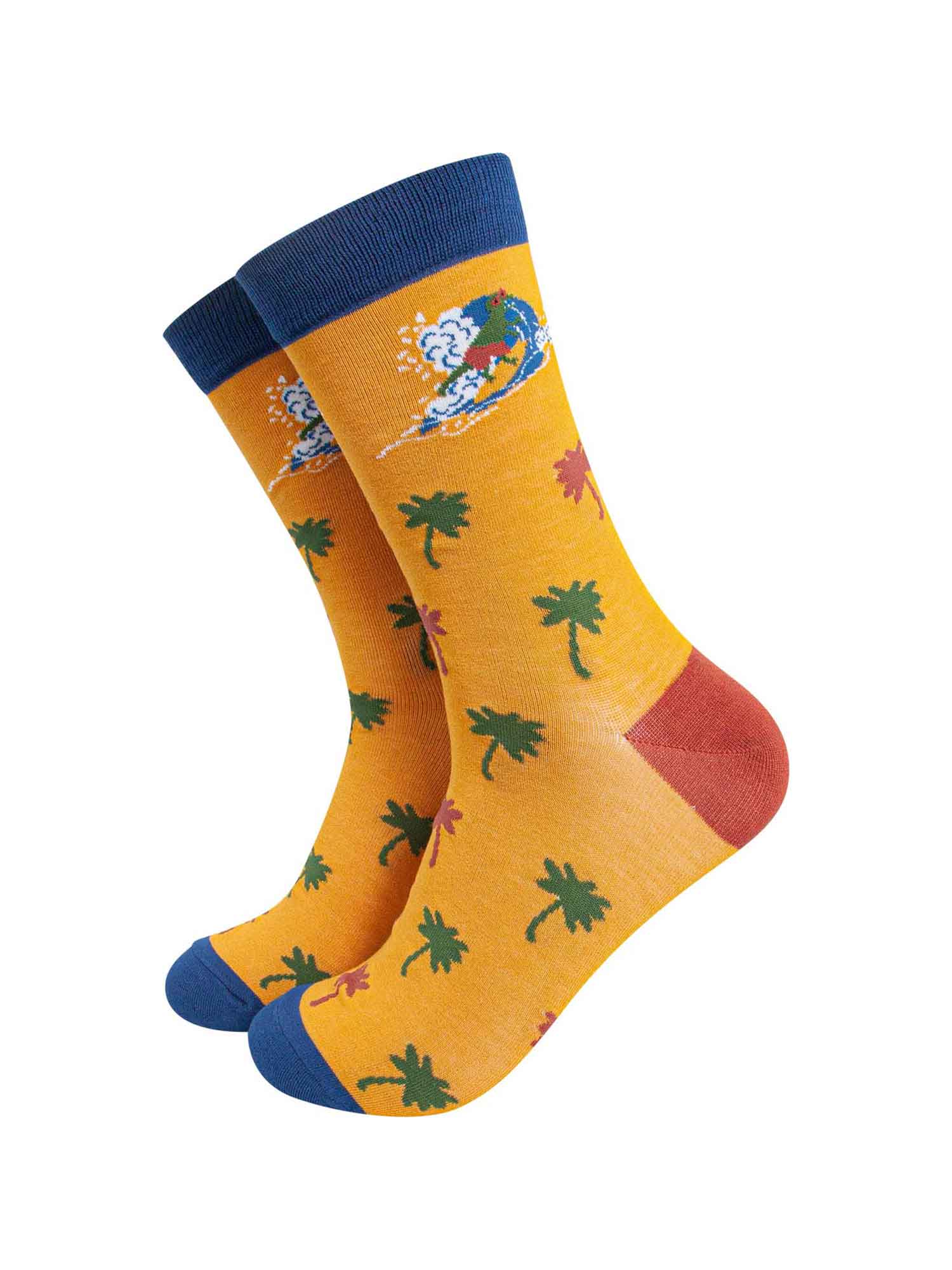 mens yellow bamboo socks featuring a surfing t-rex and an all over palm tree pattern