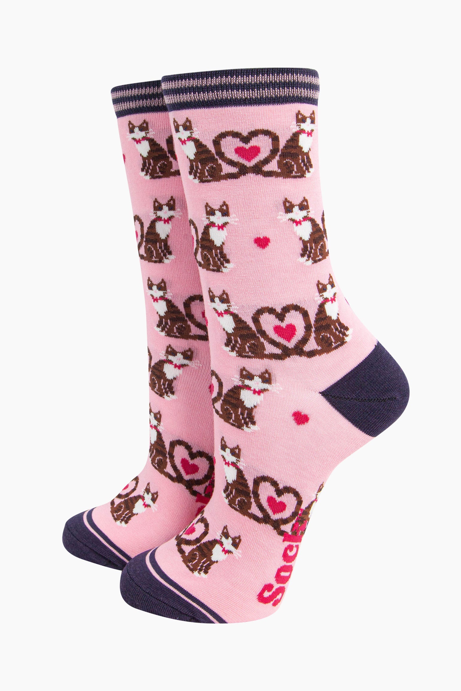 light pink bamboo socks with a pattern of brown tabby cats, their tails entwined to form a love heart shape. among the cats are fuchsia pink love heats. the heel and toe of the socks is navy blue. the cuff navy blue and pink striped.