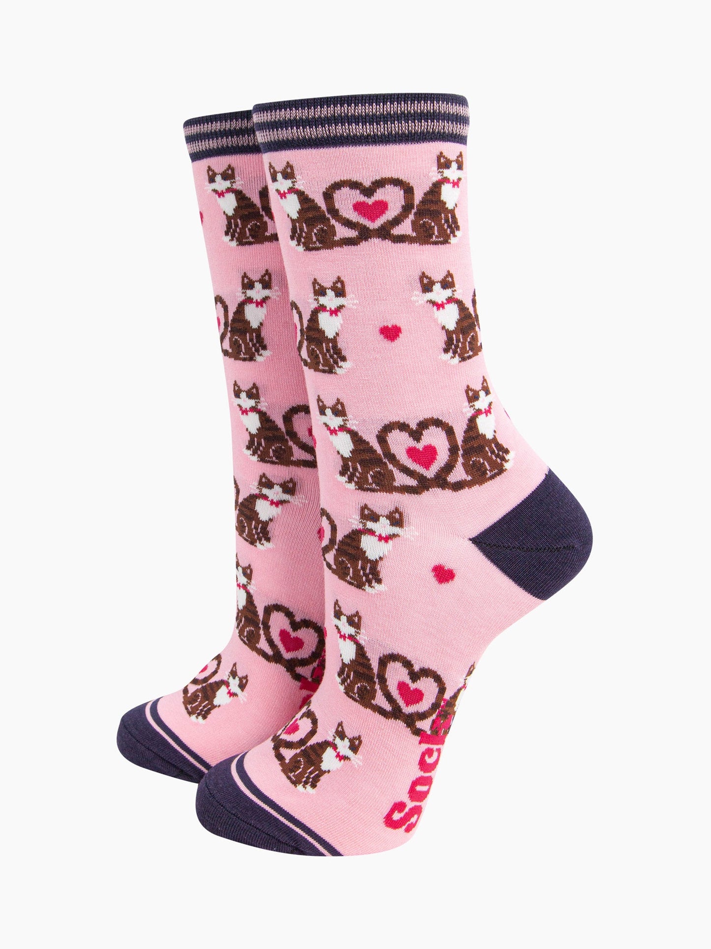 light pink bamboo socks with a pattern of brown tabby cats, their tails entwined to form a love heart shape. among the cats are fuchsia pink love heats. the heel and toe of the socks is navy blue. the cuff navy blue and pink striped.