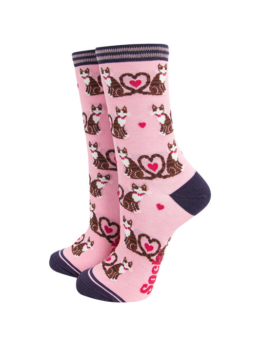 light pink bamboo socks with a pattern of brown tabby cats, their tails entwined to form a love heart shape. among the cats are fuchsia pink love heats. the heel and toe of the socks is navy blue. the cuff navy blue and pink striped.