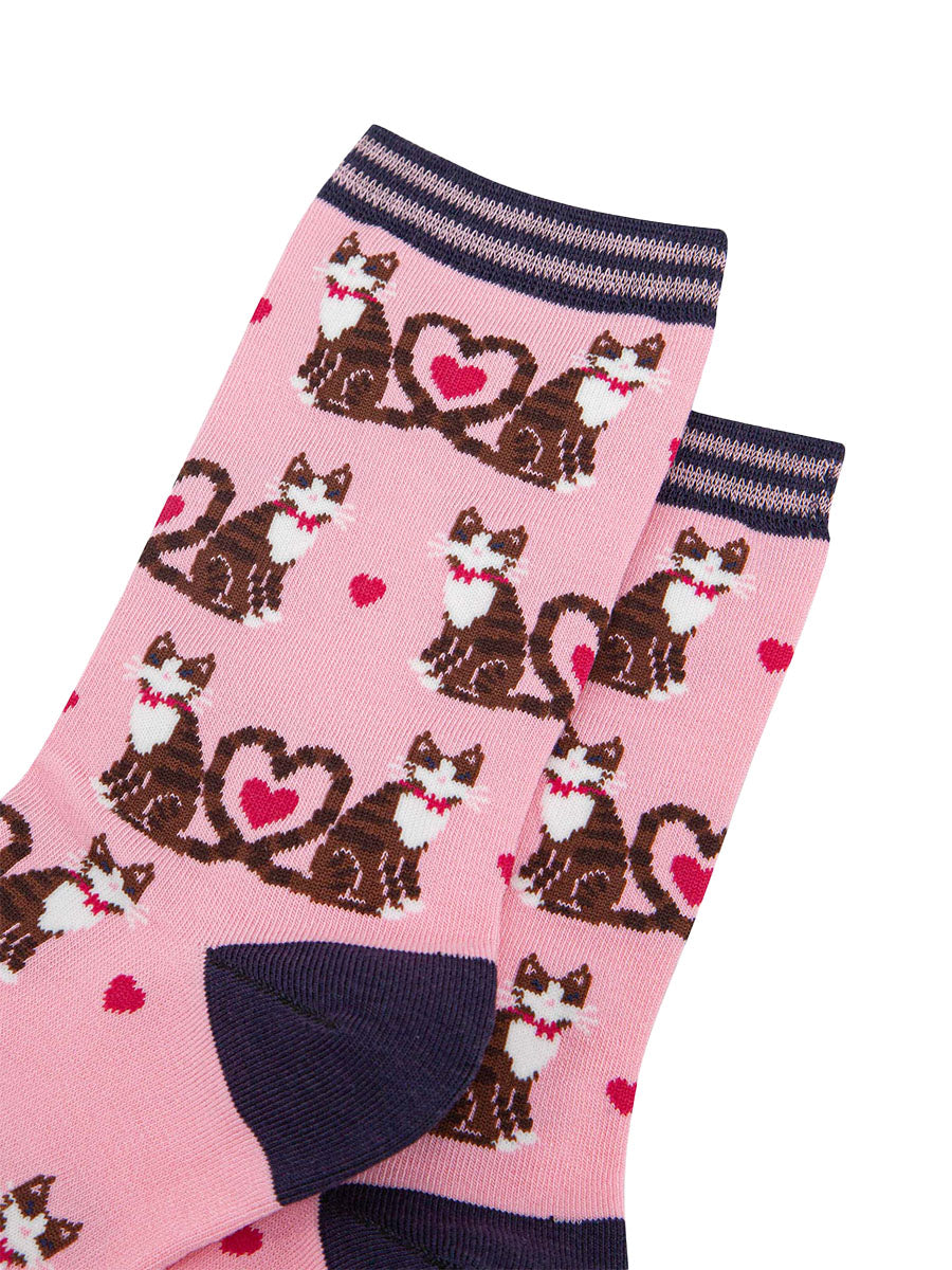 close up of the pattern. the cats are brown tabby striped and are wearing pink bow ties. Their tails are entwined in a love heart shaped loop. in the centre of the loop is a fuchsia pink love heart. there are smaller fuchsia pink love hearts scattered among the cats.