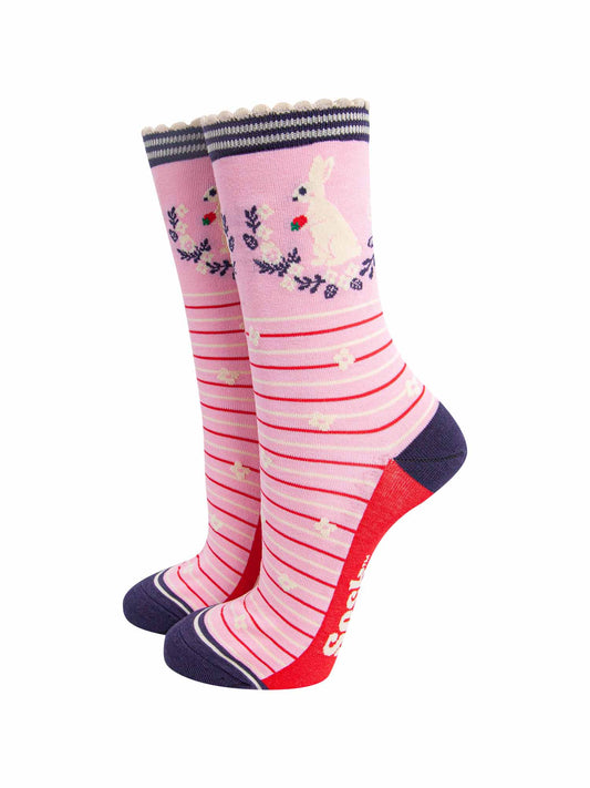 pink rabbit, wreath and strawberry bamboo socks. light pink bamboo socks with red and cream. on the ankle of the socks there is a white rabbit holding a strawberry. the wreath around the rabbit is navy blue and white.