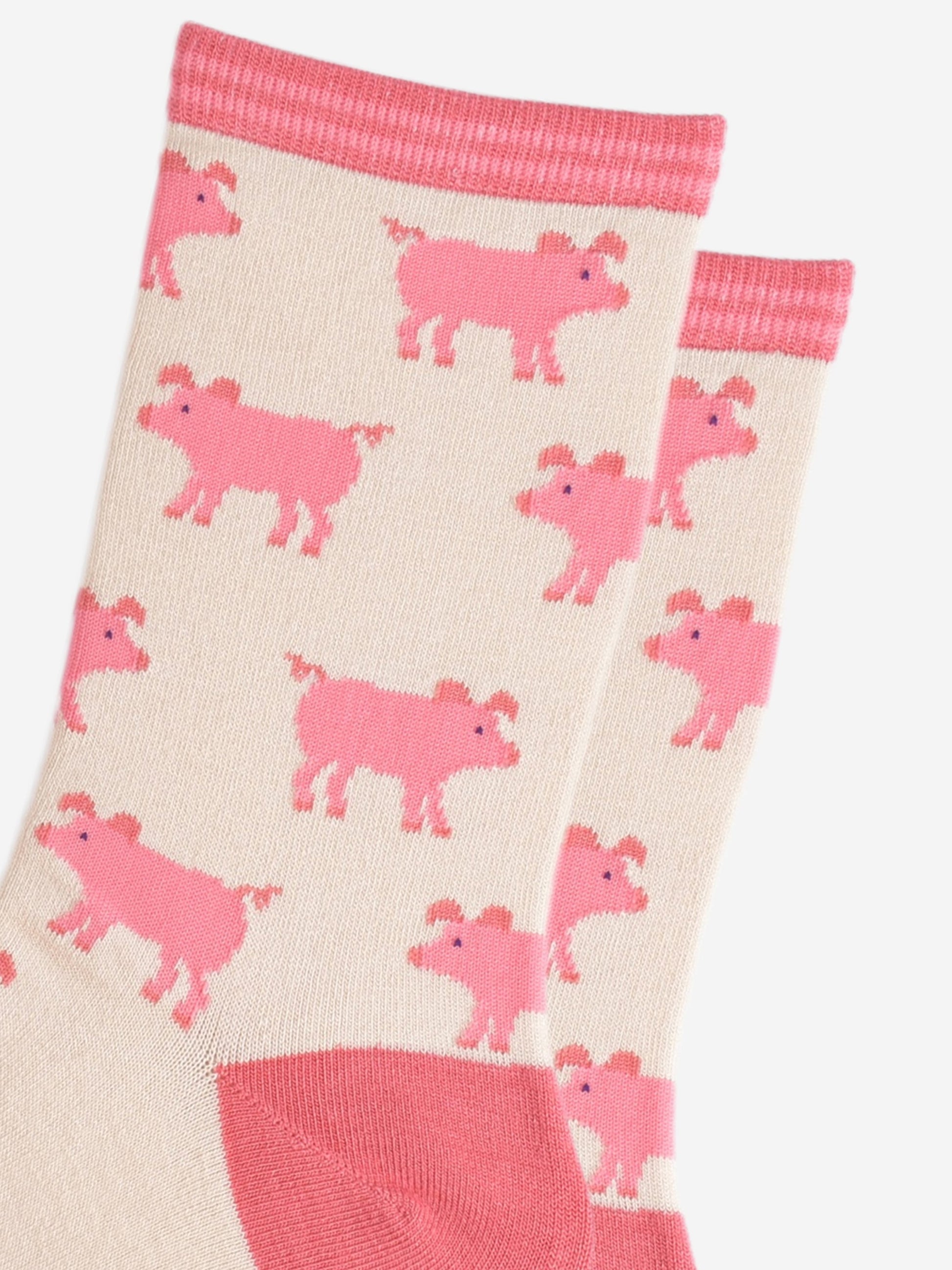 close up of the pink pig pattern on the cream bamboo socks, the pigs have curly tails and floppy ears
