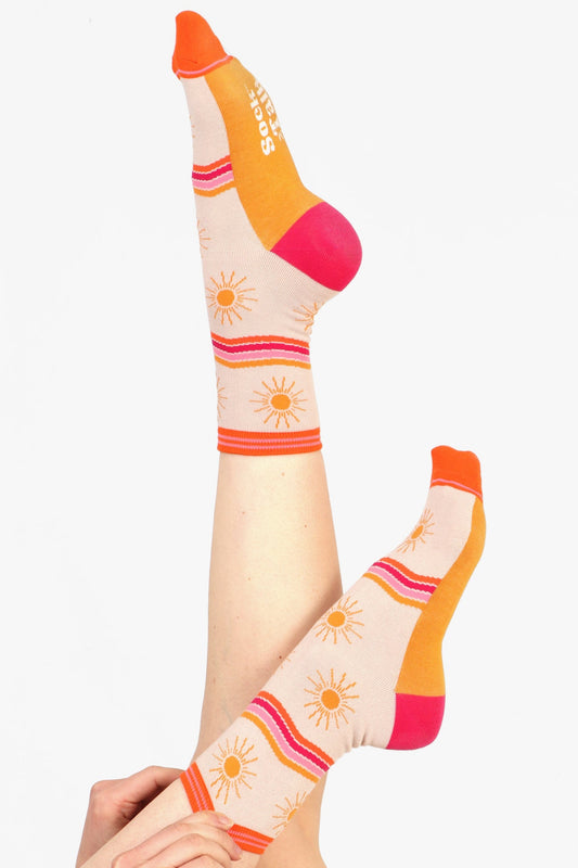 Model with legs in air wearing womens bamboo printed socks with sun and stripe design. 