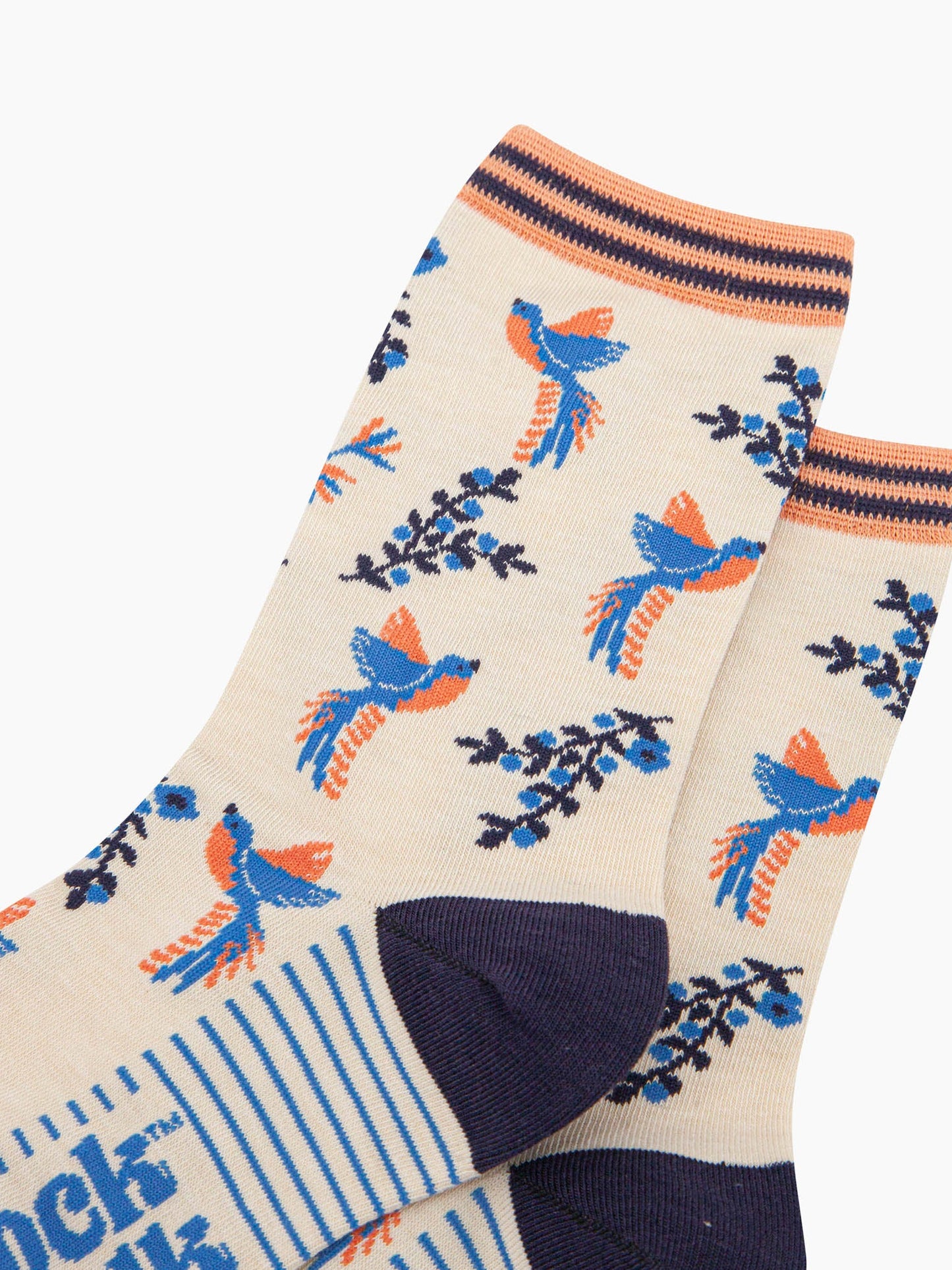 close up of the hummingbird pattern on the cream bamboo socks. the birds are blue with orange bellies. the floral vines are navy blue with light blue flowers. the hummingbirds are shown to be hovering in flight next to the flowers.